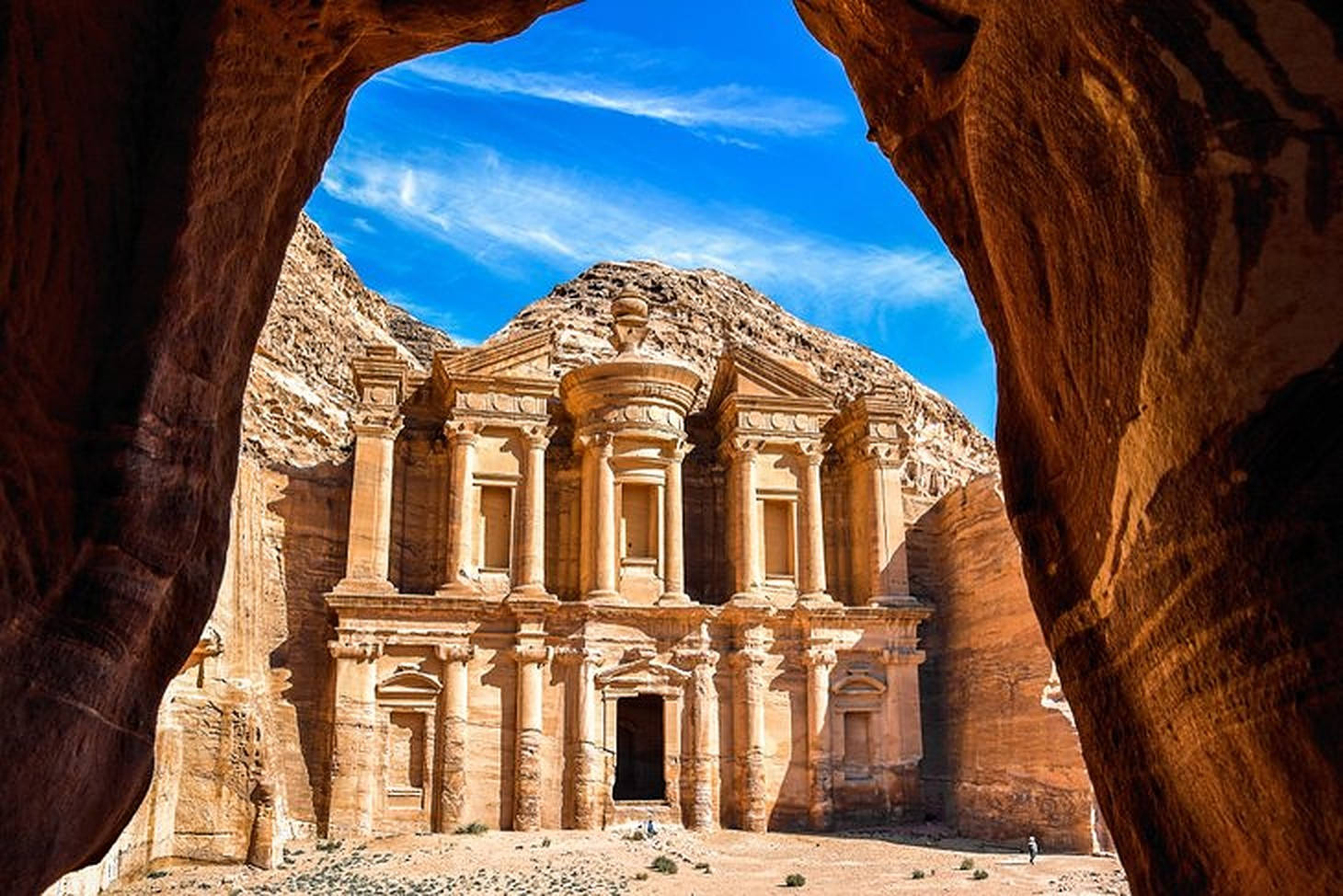 Jordan 桌布 壁紙 — 一座宏偉的古老石廟，在充滿活力的藍天下被天然岩石拱門框住。