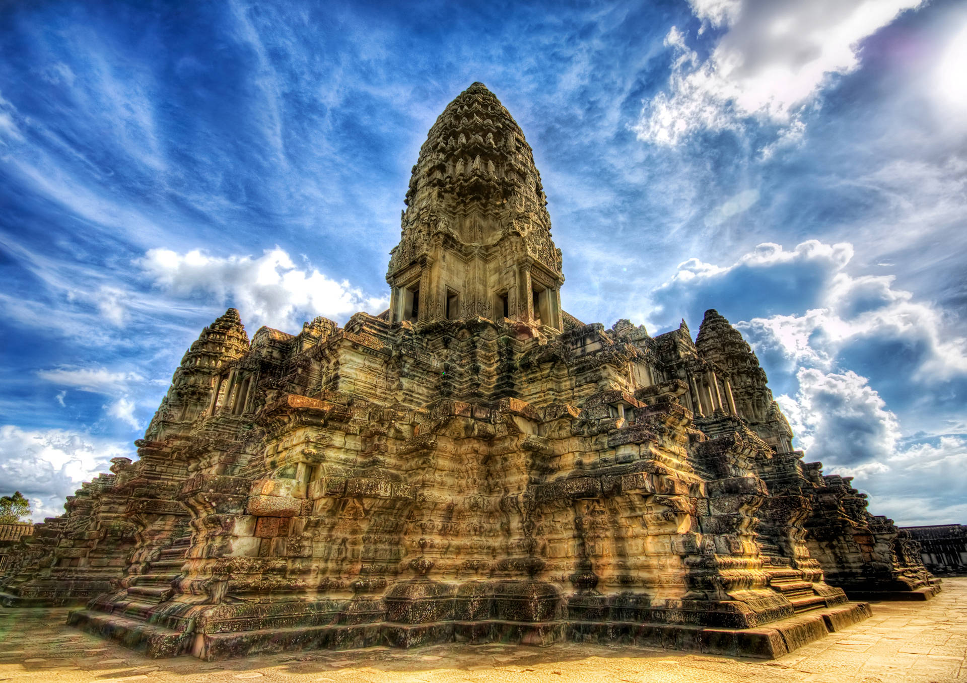 Cambodia 桌布 壁紙 — 一座宏偉的古老石廟，雕刻精細，在藍天白雲的映襯下巍然聳立。
