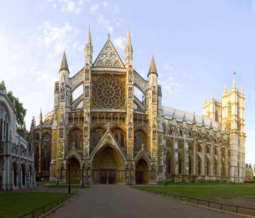 Gothic Architecture 桌布 壁紙 — 一座宏偉的哥德式大教堂，擁有精緻的石雕工藝和一個巨大的玫瑰窗，沐浴在金色的午後陽光中。