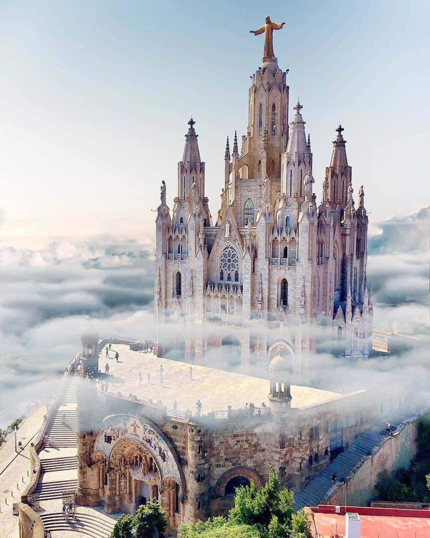 Beautiful Heaven 桌布 壁紙 — 一座宏偉的哥德式大教堂聳立於雲海之上，頂端有一座金色的基督雕像，在晴朗的天空下閃耀。