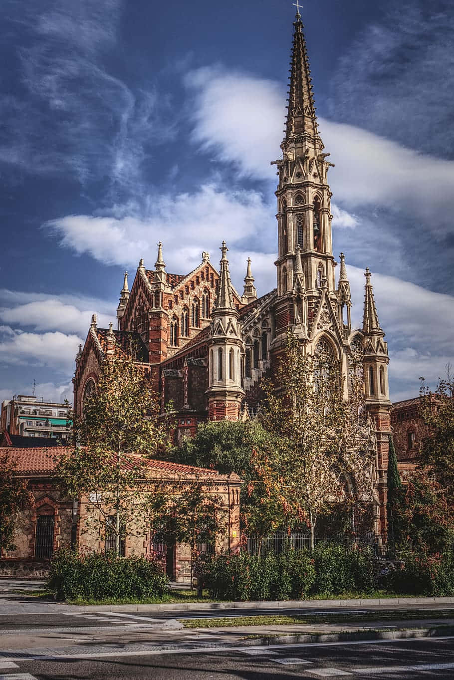 Barcelona 桌布 壁紙 — 一座宏偉的哥德式教堂，高聳的尖塔矗立在戲劇性的藍天下，伴隨著縷縷輕雲。