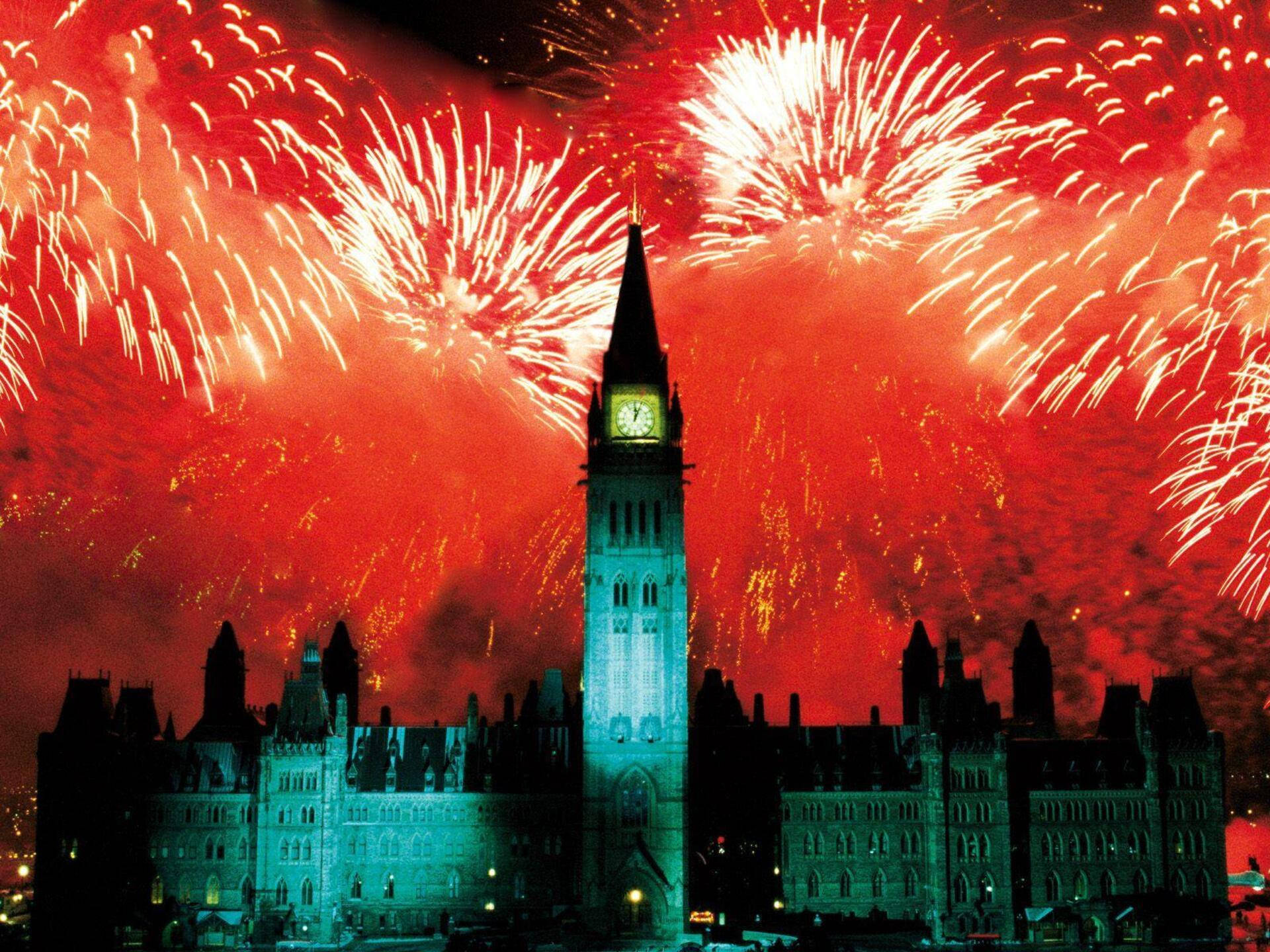 Canada Day 桌布 壁紙 — 一座宏偉的哥德式鐘樓在佈滿鮮豔紅色和白色煙火的天空中呈現剪影。