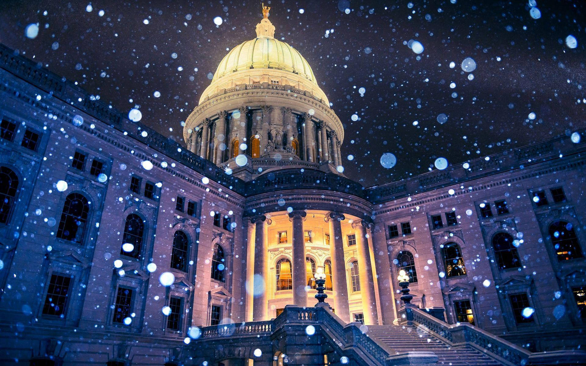 建築 桌布 壁紙 — 一座宏偉的圓頂國會大廈在雪夜中亮起燈光，閃爍的散景雪花飄落。