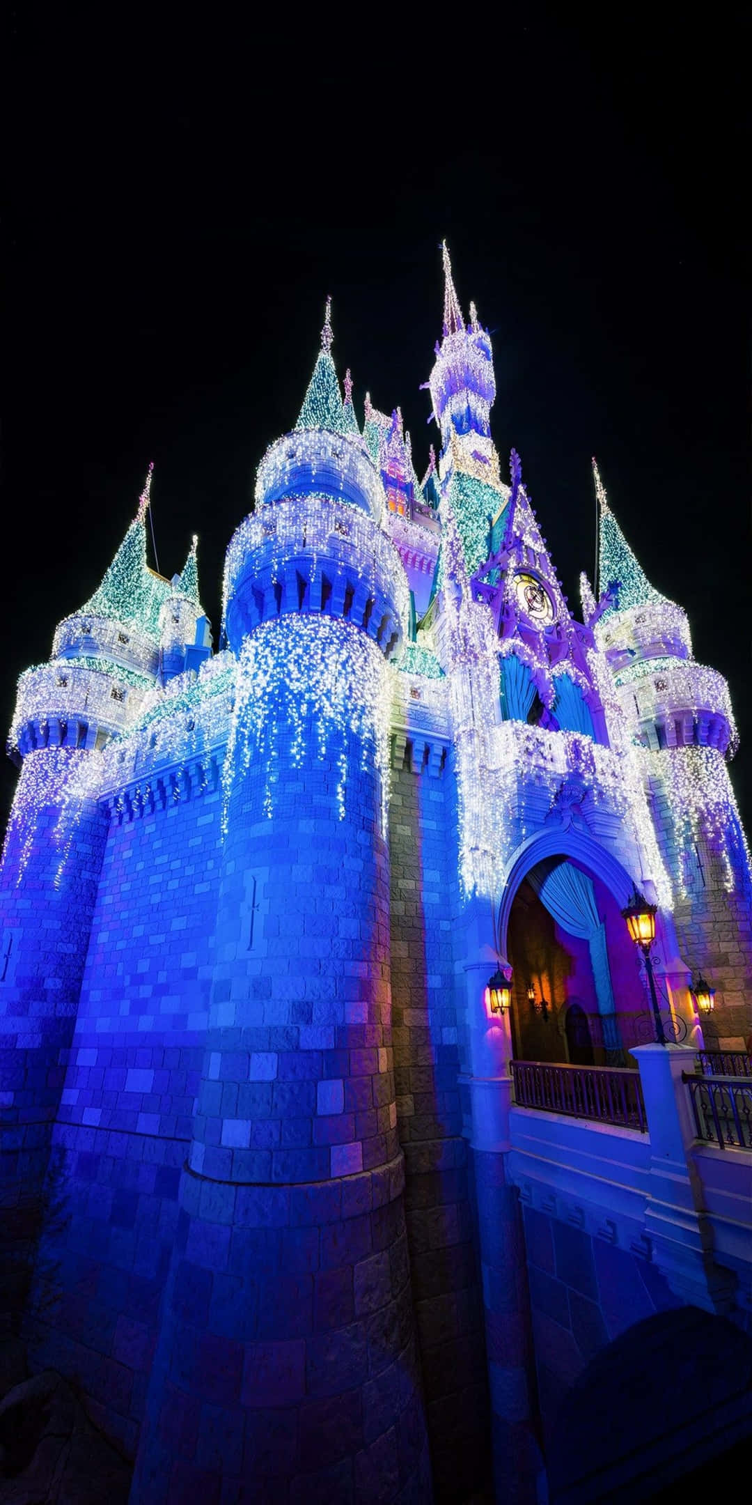 Pixel 3 Disney 桌布 壁紙 — 一座宏偉的城堡，在漆黑的夜空中被藍色和紫色的燈光層層照亮。