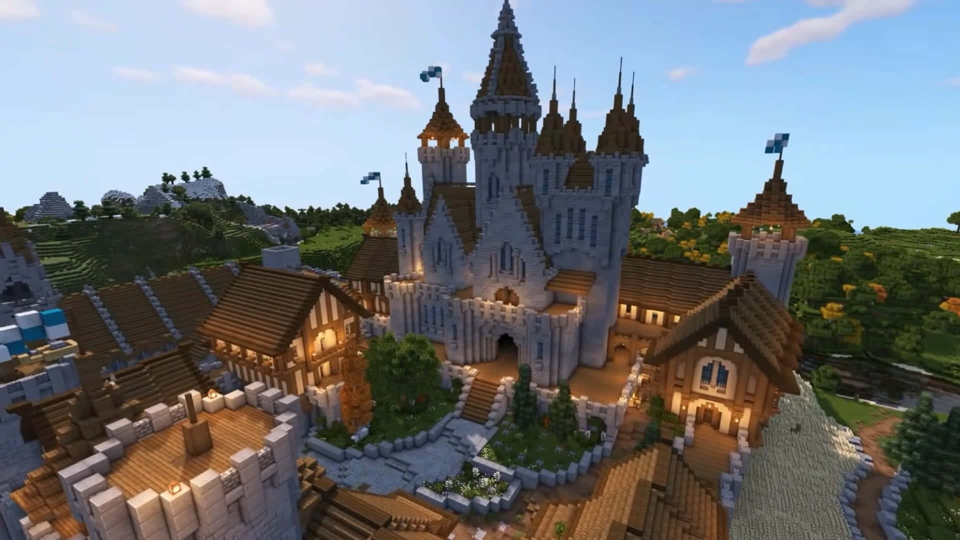 Minecraft Castles 桌布 壁紙 — 一座宏偉的城堡，擁有尖塔和角樓，矗立在鬱鬱蔥蔥的綠色山谷中，上方是明亮的藍天和蓬鬆的白雲。