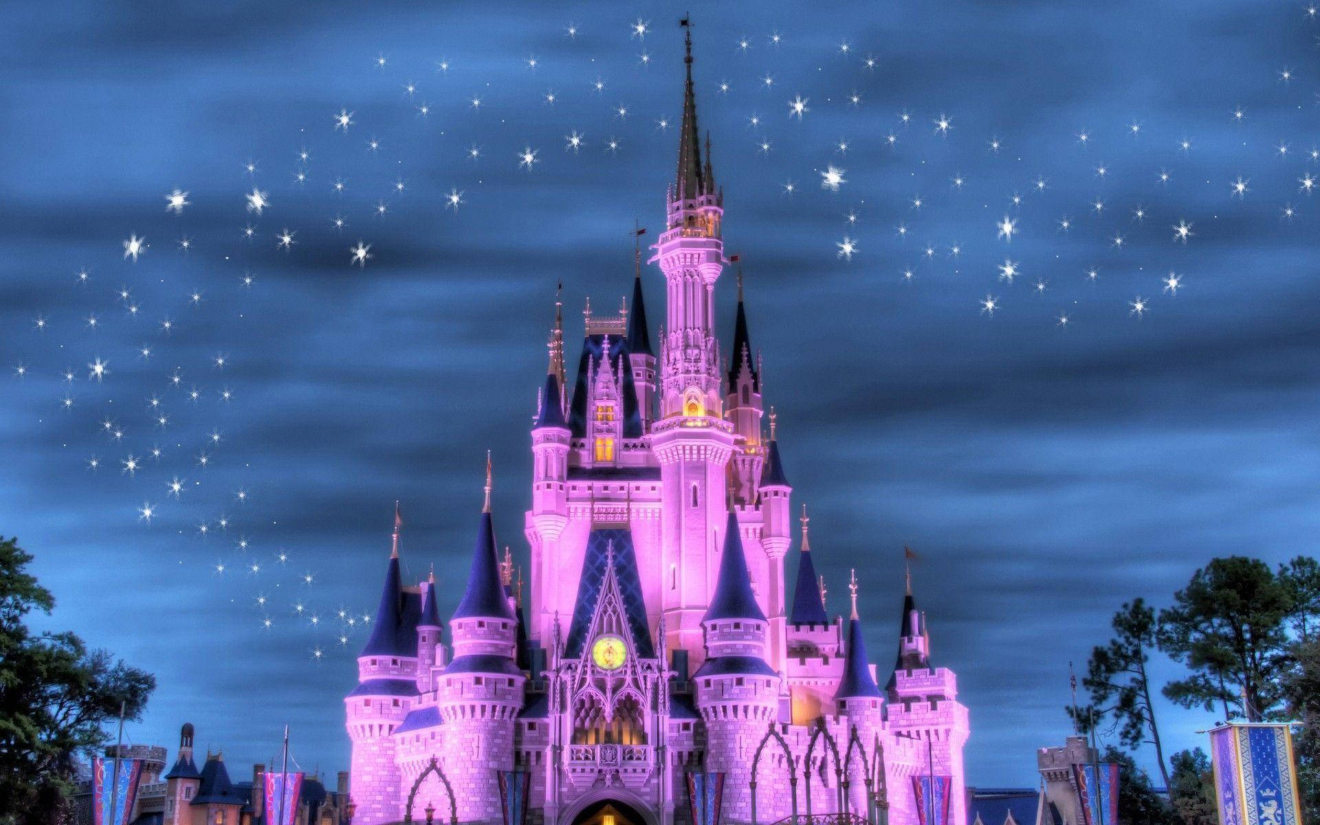 迪士尼 桌布 壁紙 — 一座宏偉的城堡沐浴在粉紅色的光芒中，矗立在繁星點點的暮色天空下，閃耀的塔樓和黑暗的尖頂。