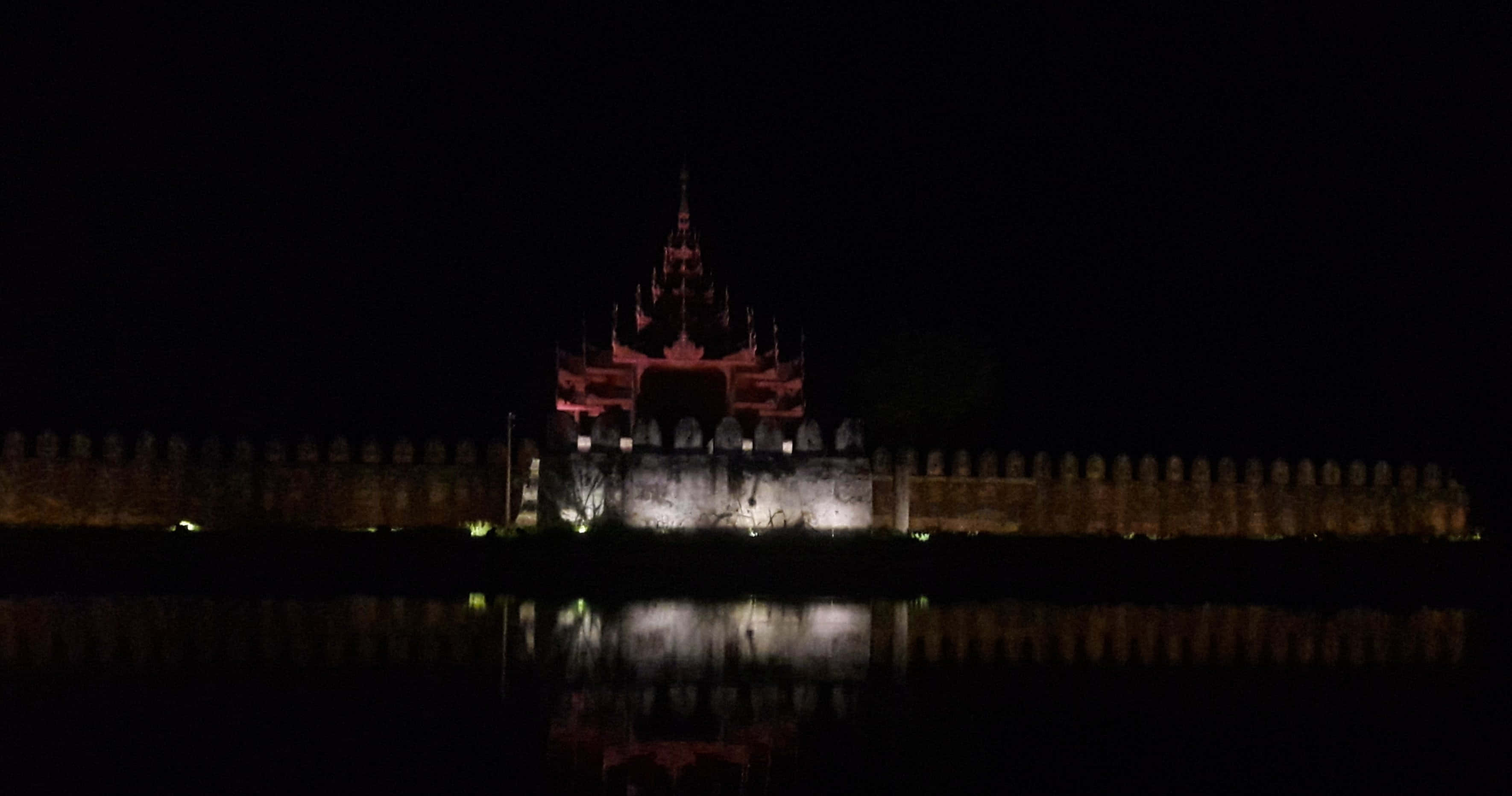Night Aesthetic 桌布 壁紙 — 一座宏偉的寺廟在紅色燈光下，以剪影姿態矗立在夜空之中，其倒影在下方平靜的水面上閃爍。