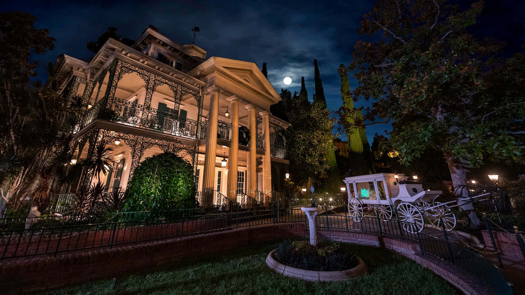 Haunted House 桌布 壁紙 — 一座宏偉的戰前時期豪宅在夜晚被照亮，一輛白色馬車停在滿月下。