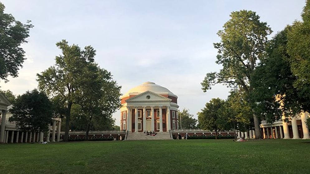 University Of Virginia 桌布 壁紙 — 一座宏偉的新古典主義圓頂建築矗立在鬱鬱蔥蔥的綠色草坪中央，周圍環繞著高大的樹木，天空柔和湛藍。