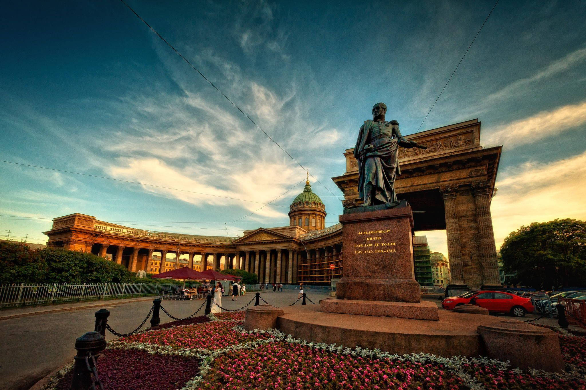 Saint Petersburg 桌布 壁紙 — 一座宏偉的新古典主義紀念碑，帶有青銅雕像，矗立在圓頂大教堂前，背景是戲劇性的日落天空。
