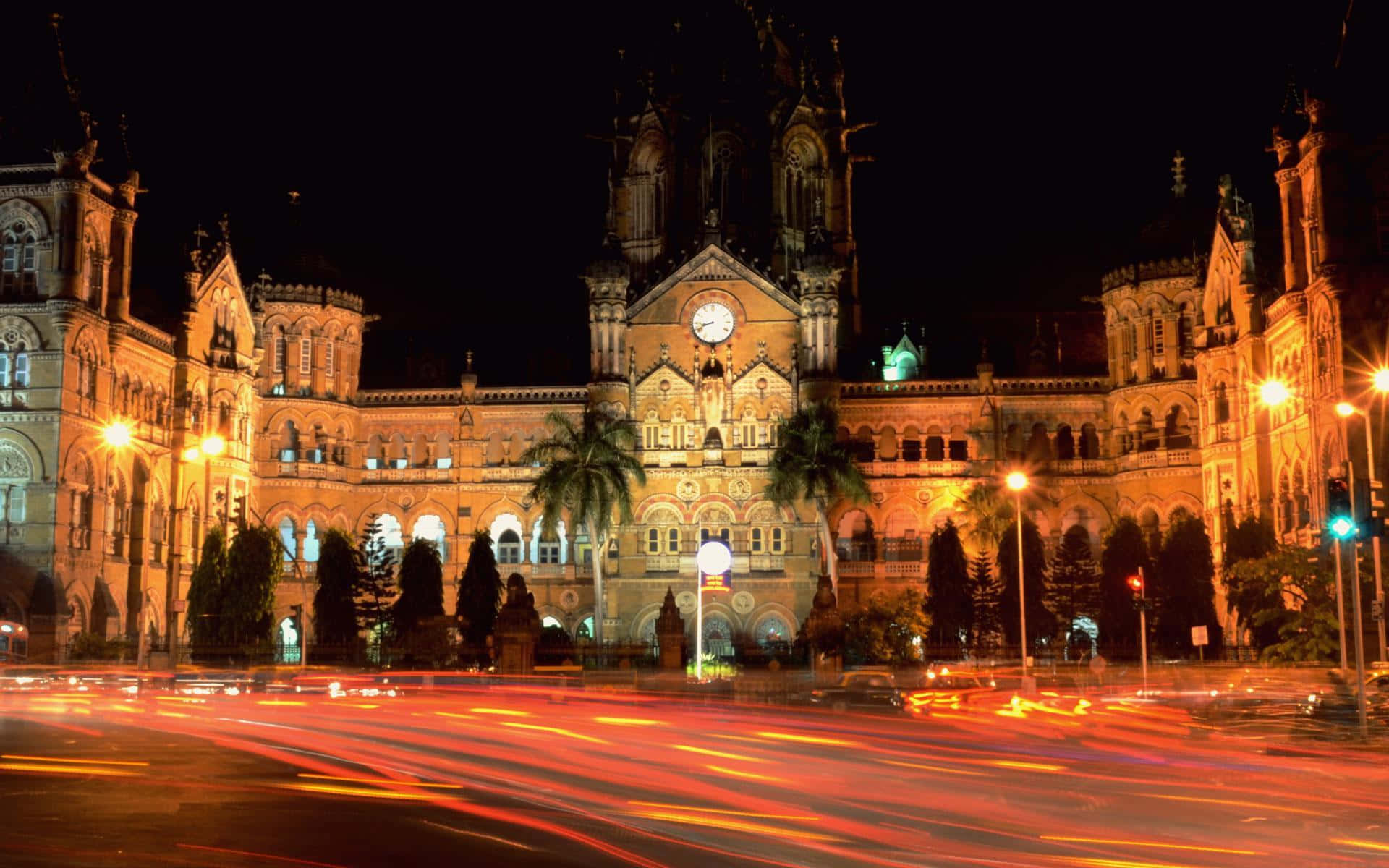 Mumbai 桌布 壁紙 — 一座宏偉的歷史建築在夜間亮起，下方車流留下鮮豔的光軌。