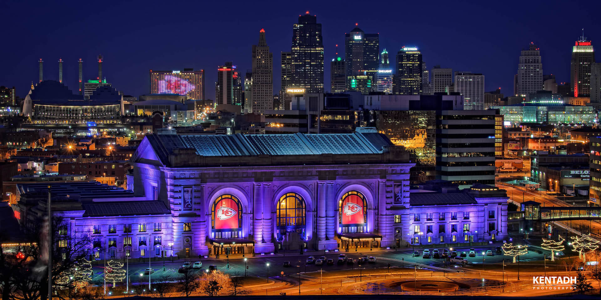 Union Station 桌布 壁紙 — 一座宏偉的歷史火車站沐浴在紫色燈光中，在夜晚充滿活力的城市天際線襯托下熠熠生輝。