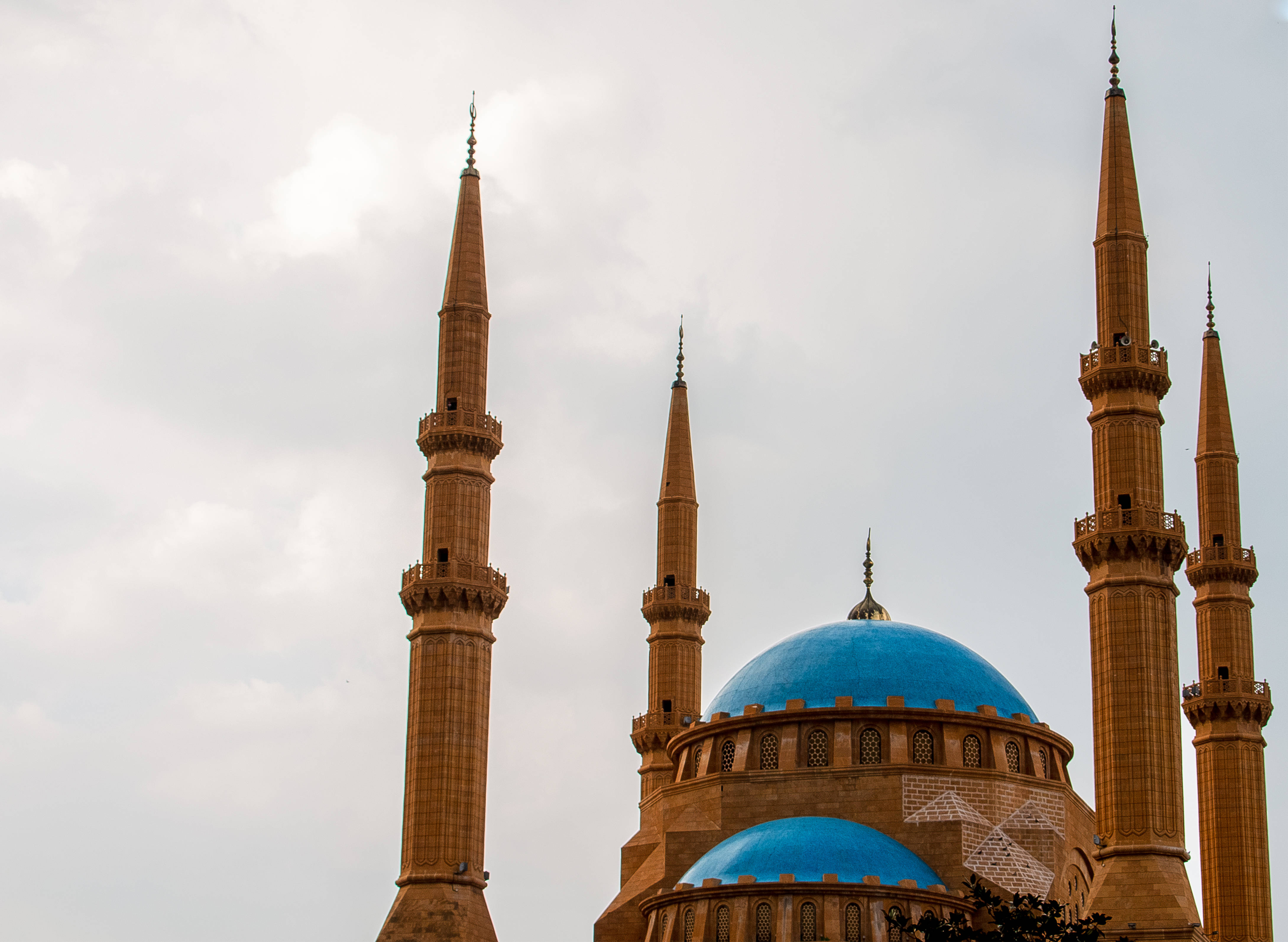 Lebanon 桌布 壁紙 — 一座宏偉的清真寺，擁有充滿活力的藍色圓頂和四座高大的石質宣禮塔，聳立在多雲的天空下。