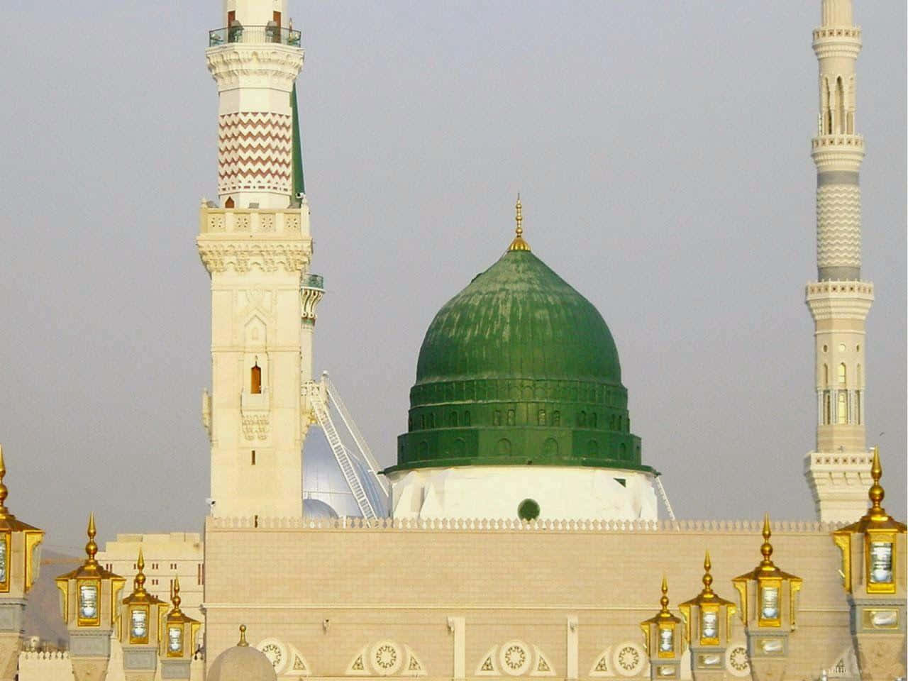 Medina 桌布 壁紙 — 一座宏偉的清真寺，擁有綠色圓頂和兩座高聳的宣禮塔，在朦朧的天空下。