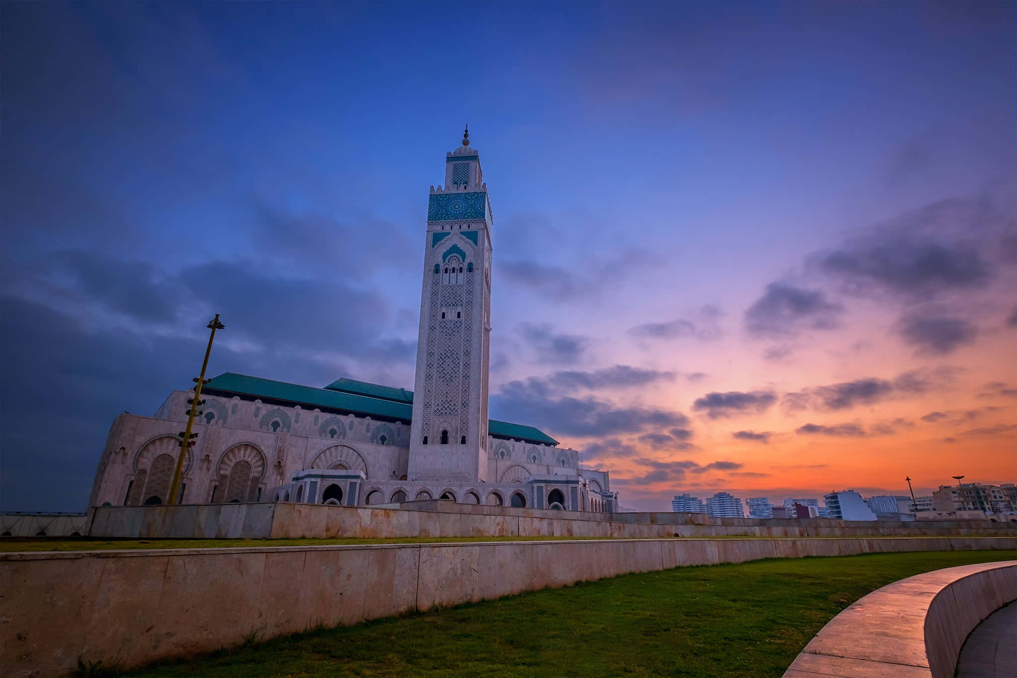 Mosque 桌布 壁紙 — 一座宏偉的清真寺，高聳的宣禮塔在佈滿橙色和紫色雲彩的 vibrant 暮色天空中呈現剪影。