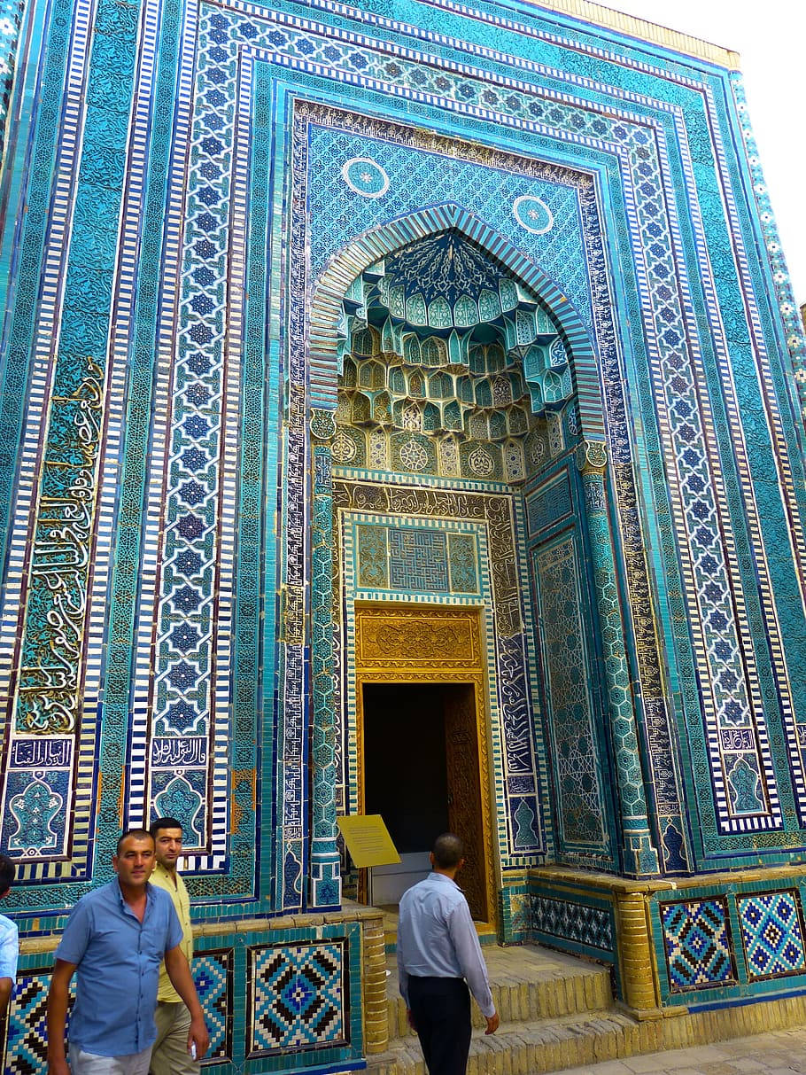 Uzbekistan 桌布 壁紙 — 一座宏偉的清真寺入口，裝飾著複雜的綠松石藍色和金色瓷磚，在明亮的日光下呈現幾何和花卉圖案。
