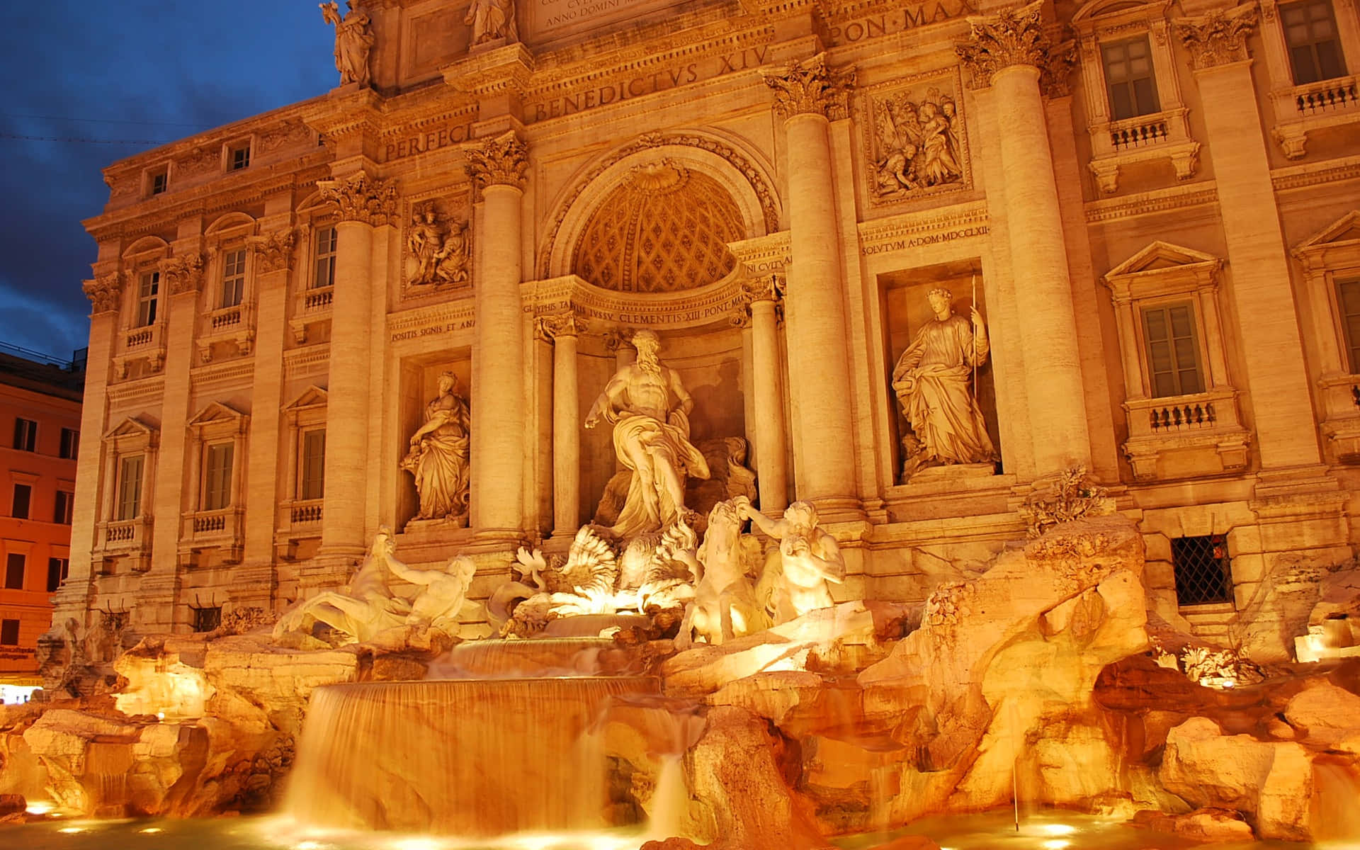 Rome 桌布 壁紙 — 一座宏偉的照明巴洛克式噴泉，在黃昏時分，流水如瀑布，大理石雕像在溫暖燈光下閃耀。