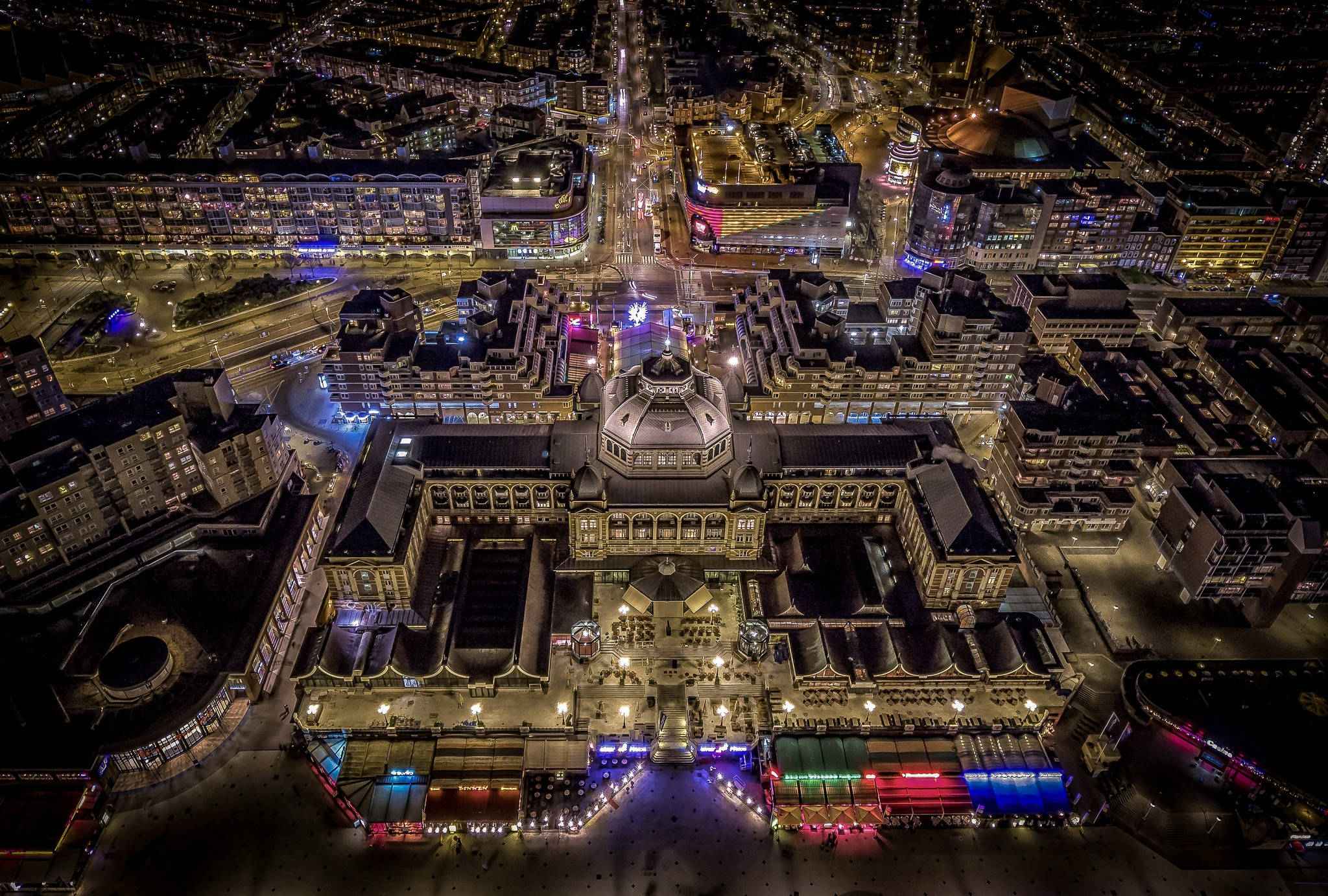 Netherlands 桌布 壁紙 — 一座宏偉的照明建築的空中夜景，周圍環繞著發光的城市街道和充滿活力的霓虹燈。