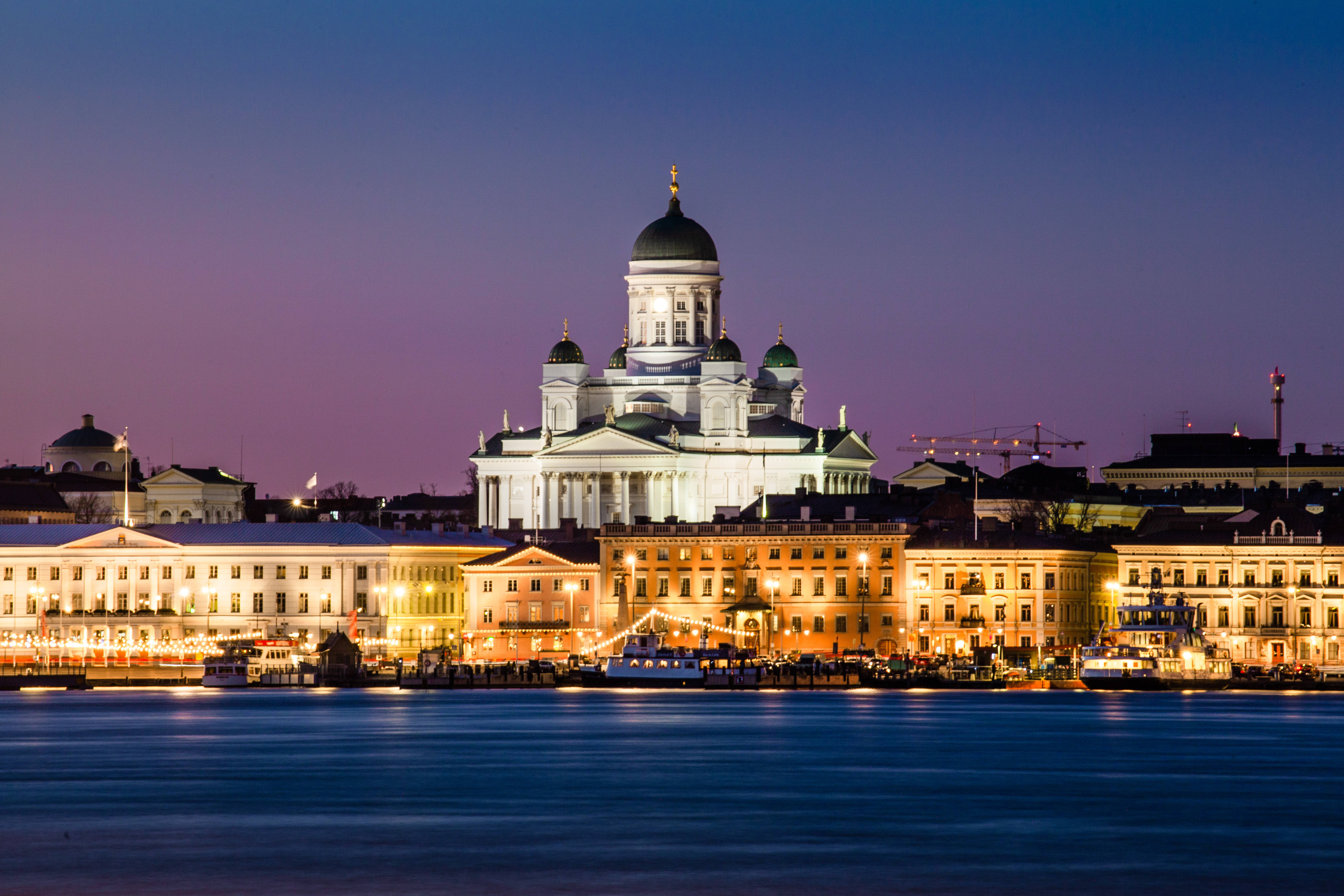 Finland 桌布 壁紙 — 一座宏偉的燈光大教堂，圓頂屋頂，在黃昏時分雄偉地矗立在海濱，燈光倒映在平靜的水面上。