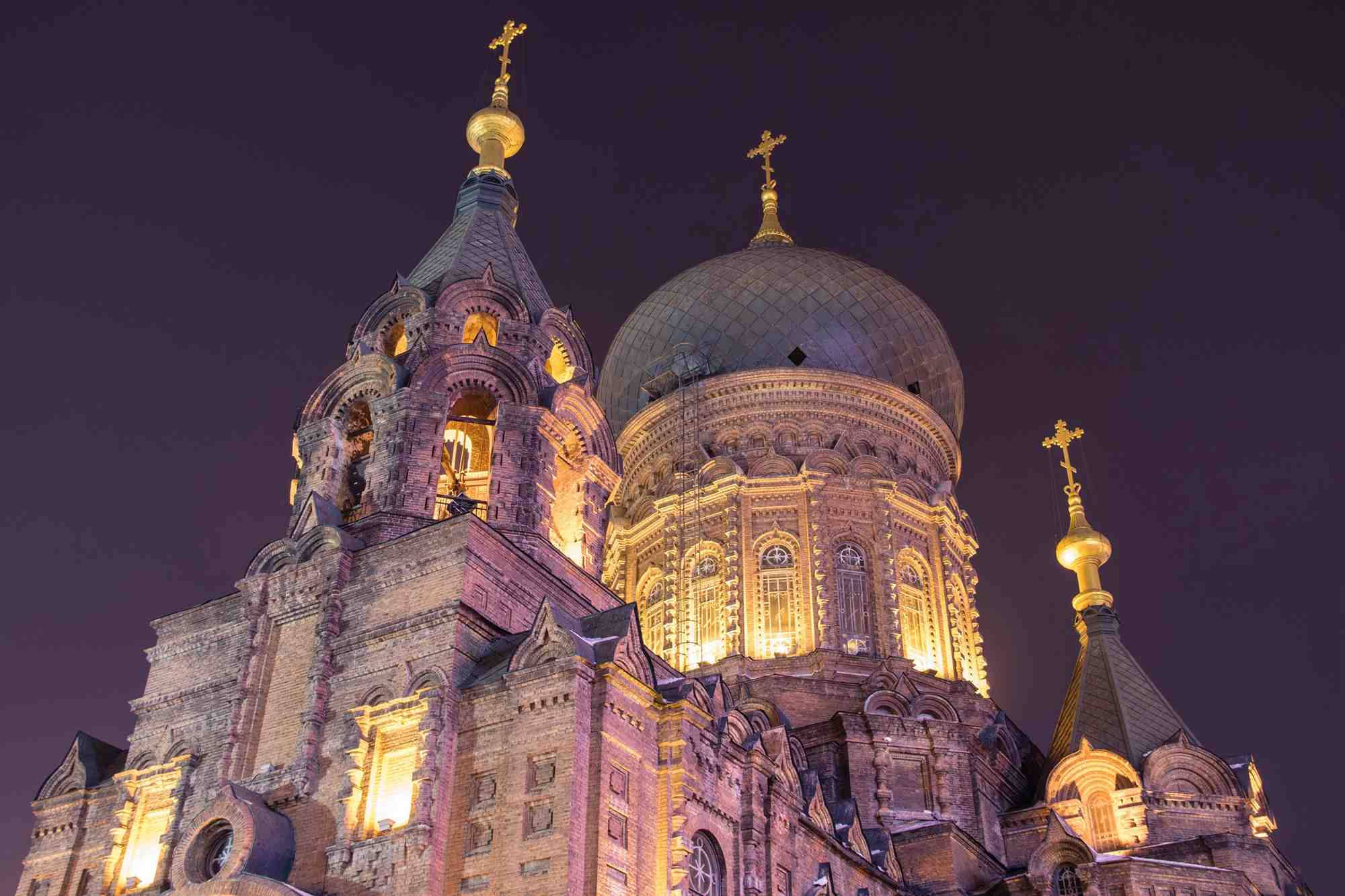Harbin 桌布 壁紙 — 一座宏偉的燈光東正教大教堂，金色圓頂和十字架在深紫色夜空中閃耀。