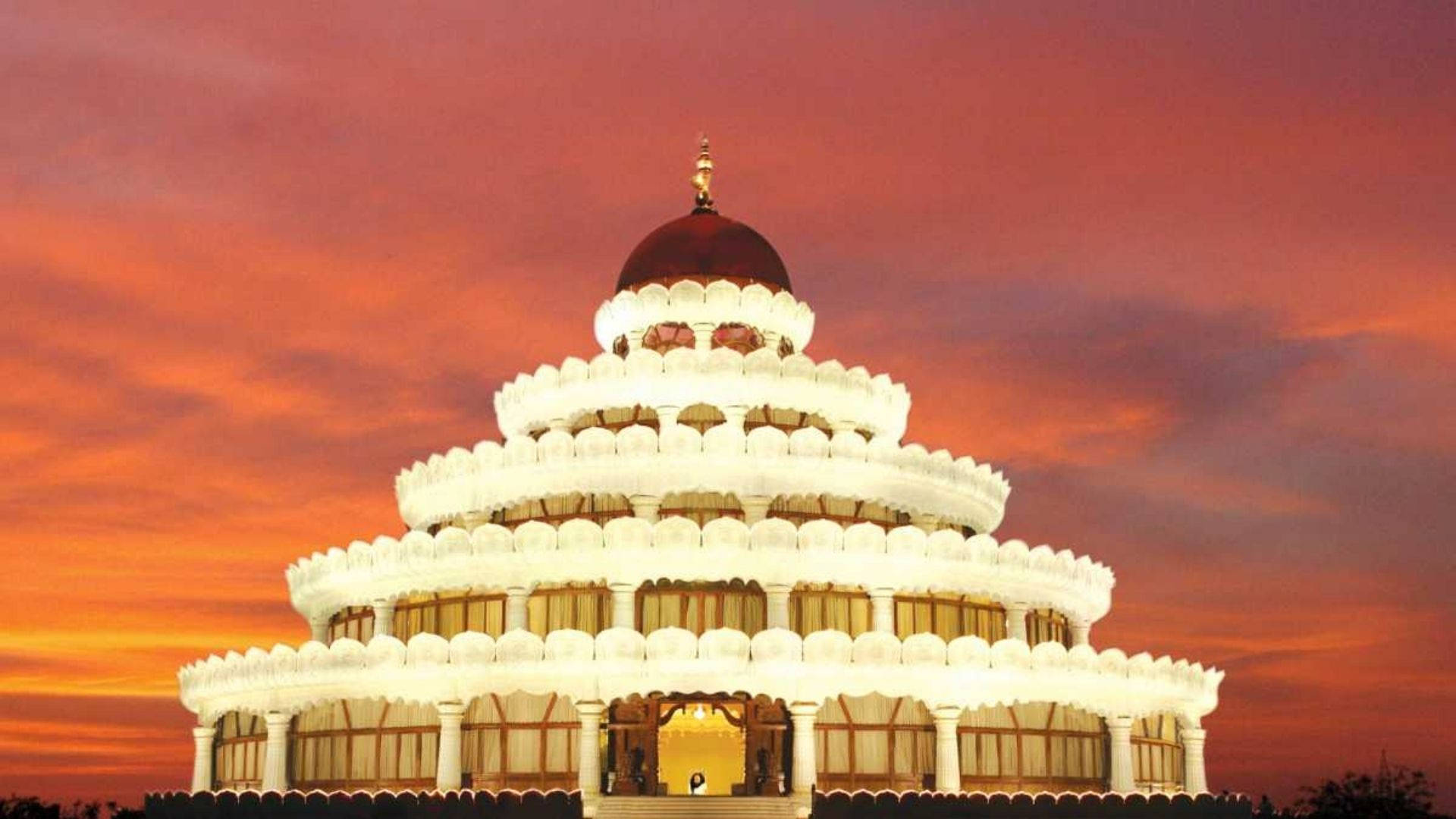 Bangalore 桌布 壁紙 — 一座宏偉的白色分層寺廟，帶有紅色圓頂，在火紅的橙色和粉紅色日落天空下閃耀。