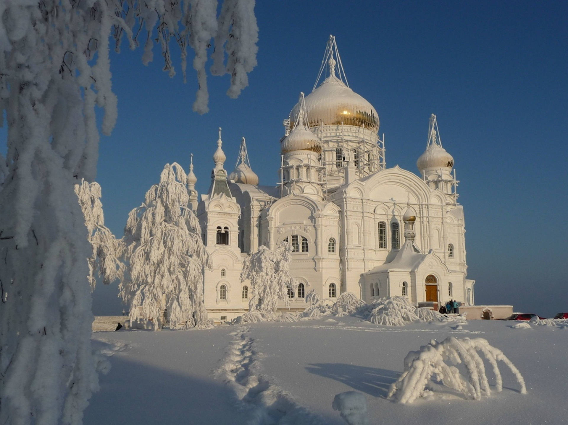 Russia 桌布 壁紙 — 一座宏偉的白色大教堂，金色圓頂在晴朗藍天下矗立於白雪皚皚的冬季景觀中。
