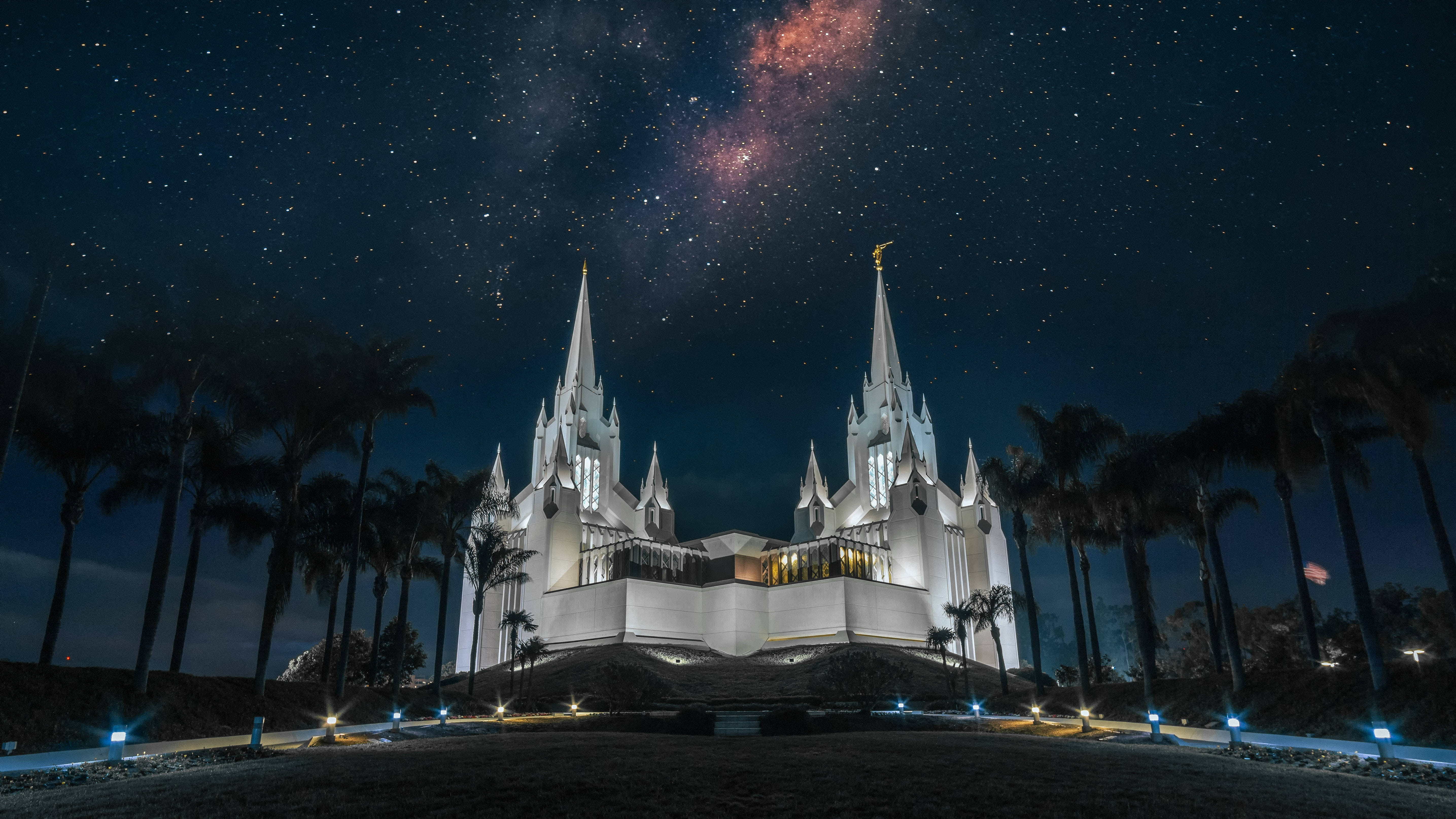 Stars 桌布 壁紙 — 一座宏偉的白色寺廟在夜晚被照亮，上方是充滿活力的星空，閃耀的銀河拱跨天際。