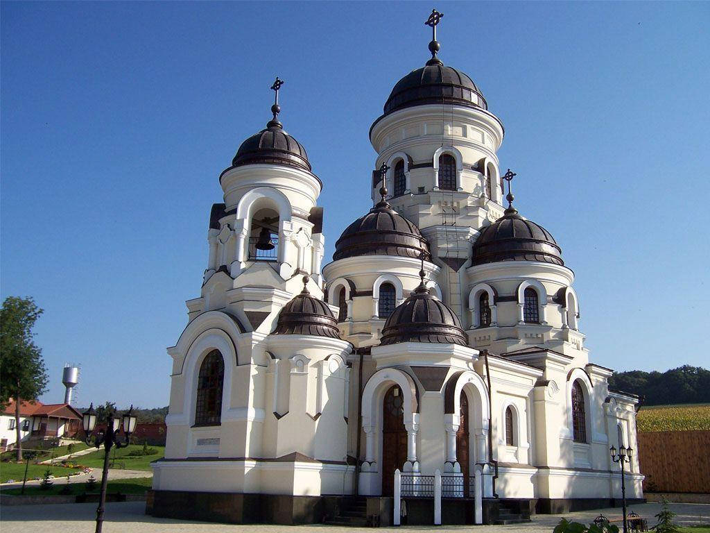 教堂 桌布 壁紙 — 一座宏偉的白色東正教教堂，帶有深色圓頂和十字架，矗立在鄉村環境中清澈的藍天下。