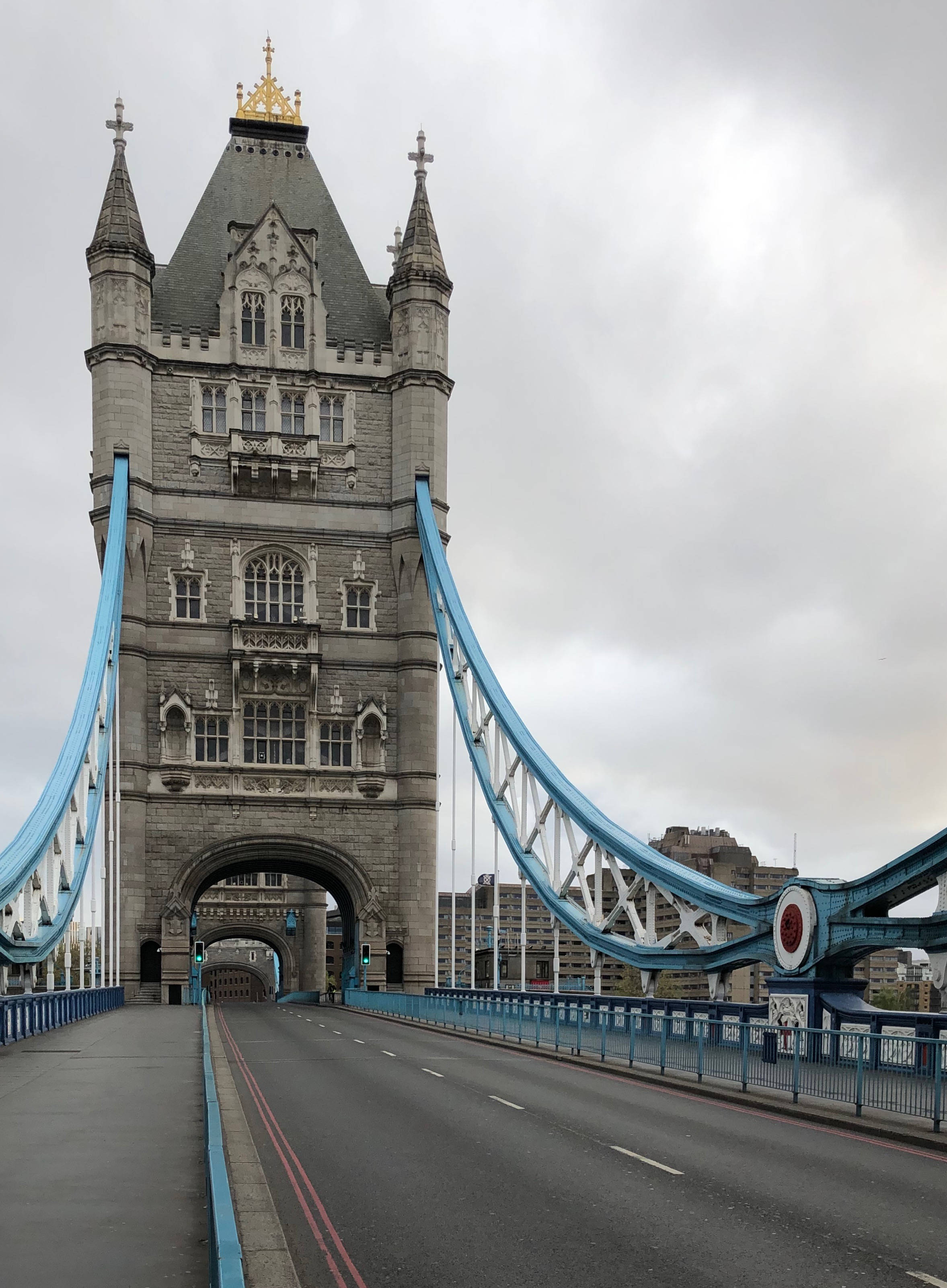 bridge 桌布 壁紙 — 一座宏偉的石塔橋，帶有藍色懸索，在陰天之下橫跨河流。