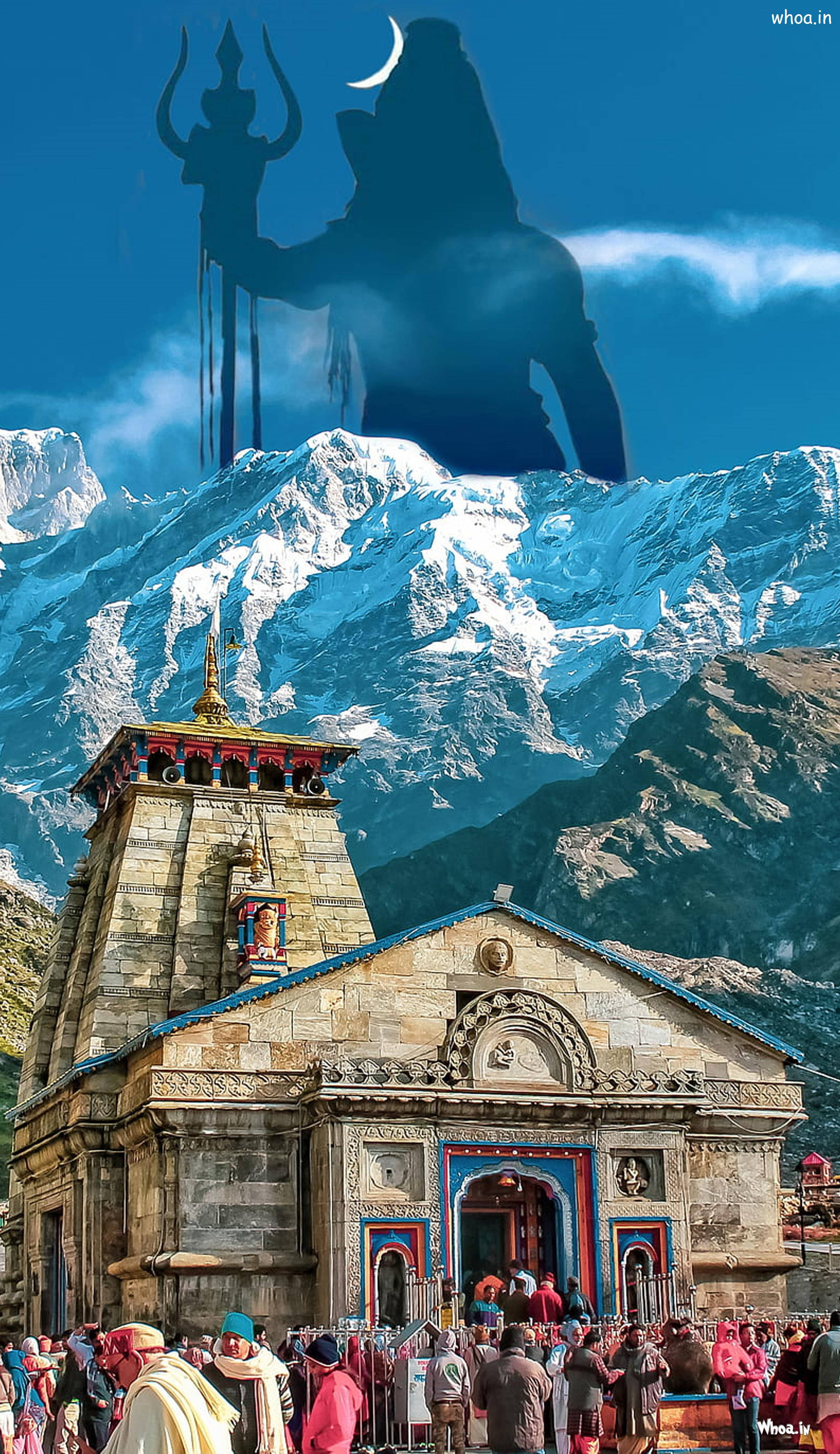 Kedarnath 桌布 壁紙 — 一座宏偉的石廟坐落在雪山腳下，上方有巨大的濕婆神影子，手持三叉戟和彎月。