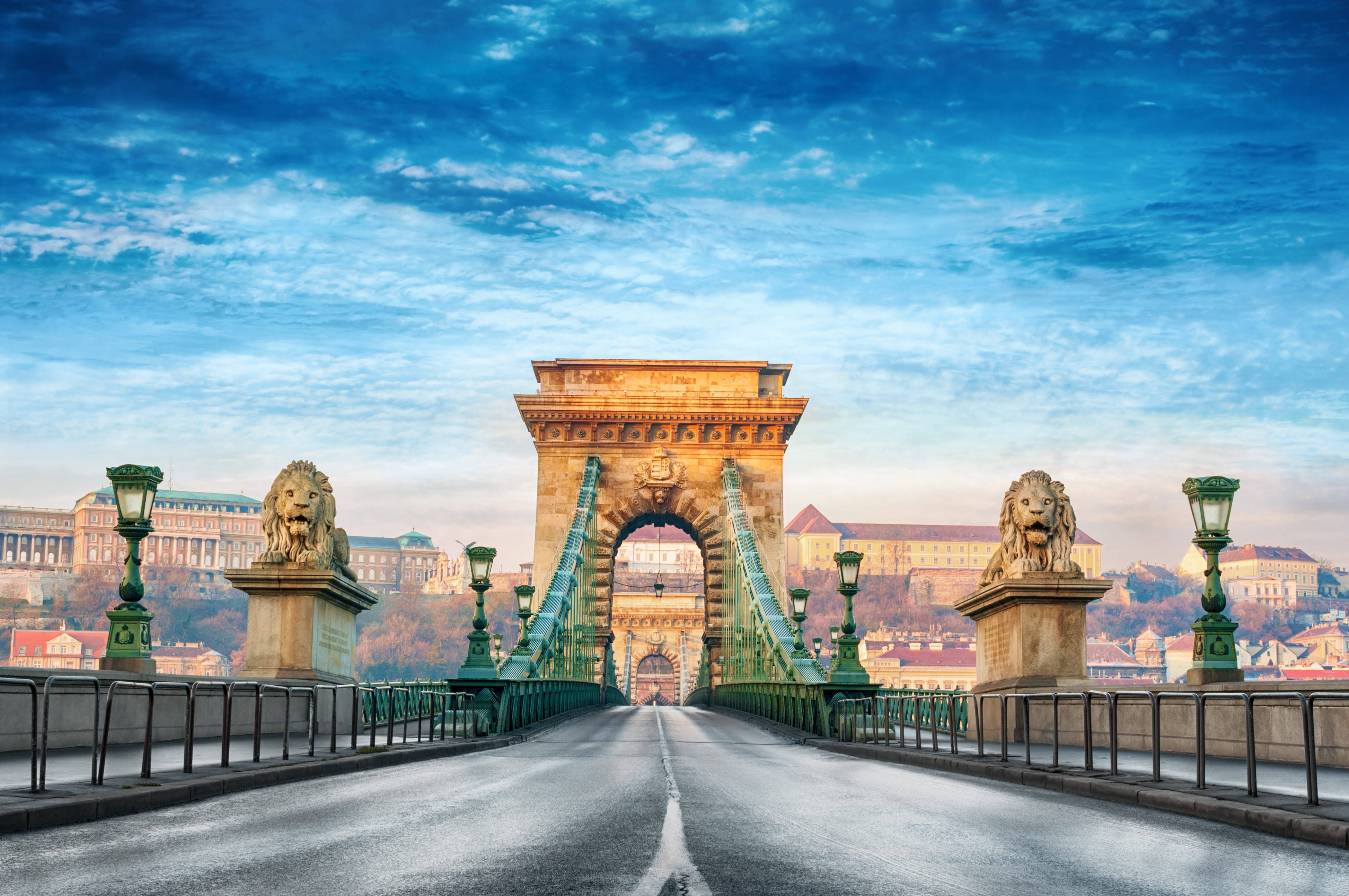 Europe 桌布 壁紙 — 一座宏偉的石橋，上有獅子雕像和綠色懸索，在藍天白雲下橫跨河流。