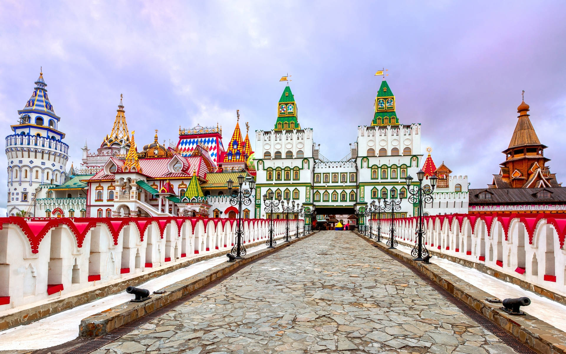 Russia 桌布 壁紙 — 一座宏偉的石橋通往一個充滿活力的童話城堡，城堡擁有色彩繽紛的尖頂和華麗的塔樓，天空多雲。