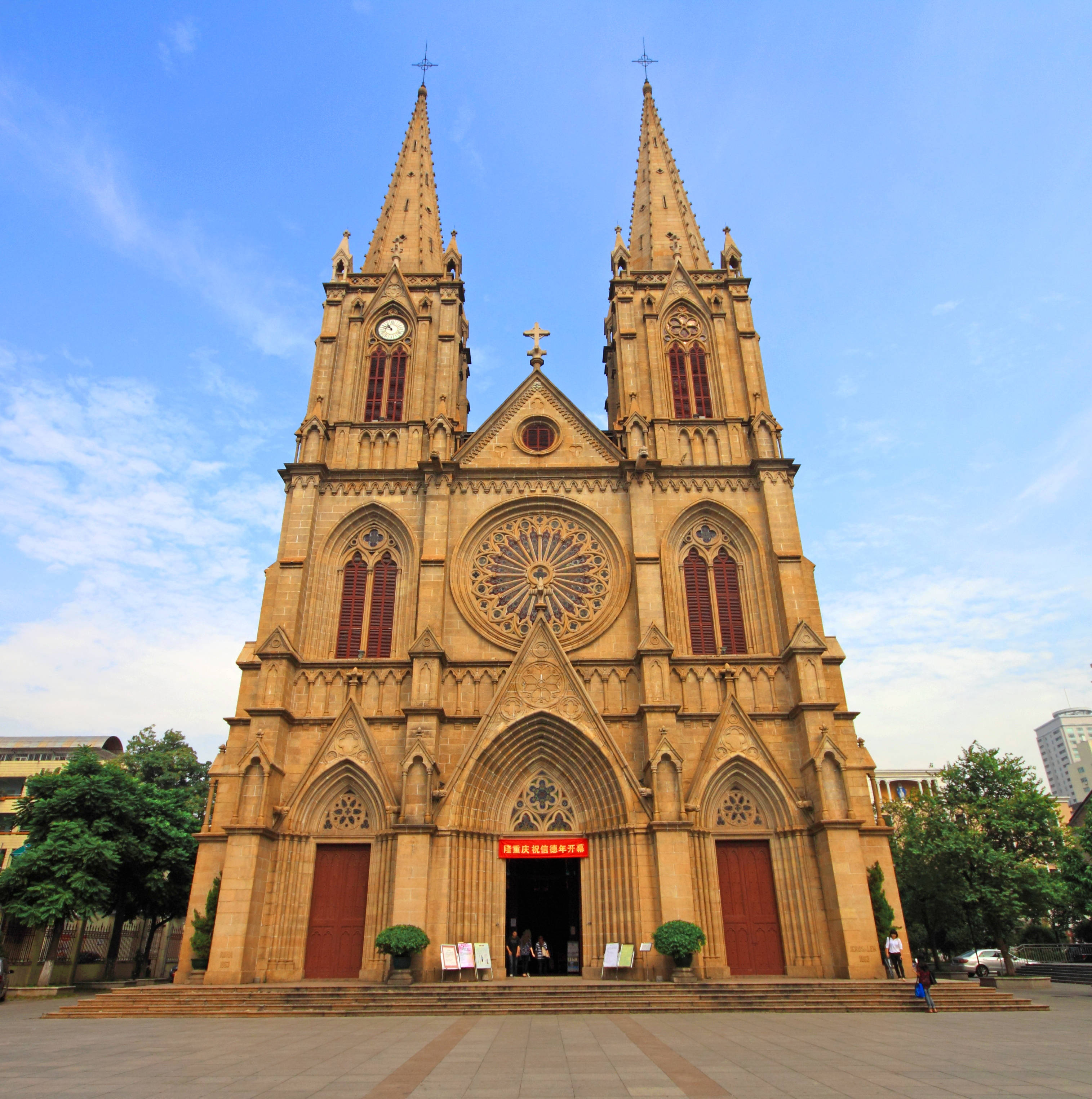 Guangzhou 桌布 壁紙 — 一座宏偉的石造大教堂，擁有雙塔和玫瑰窗，矗立在晴朗的藍天和白雲之下。