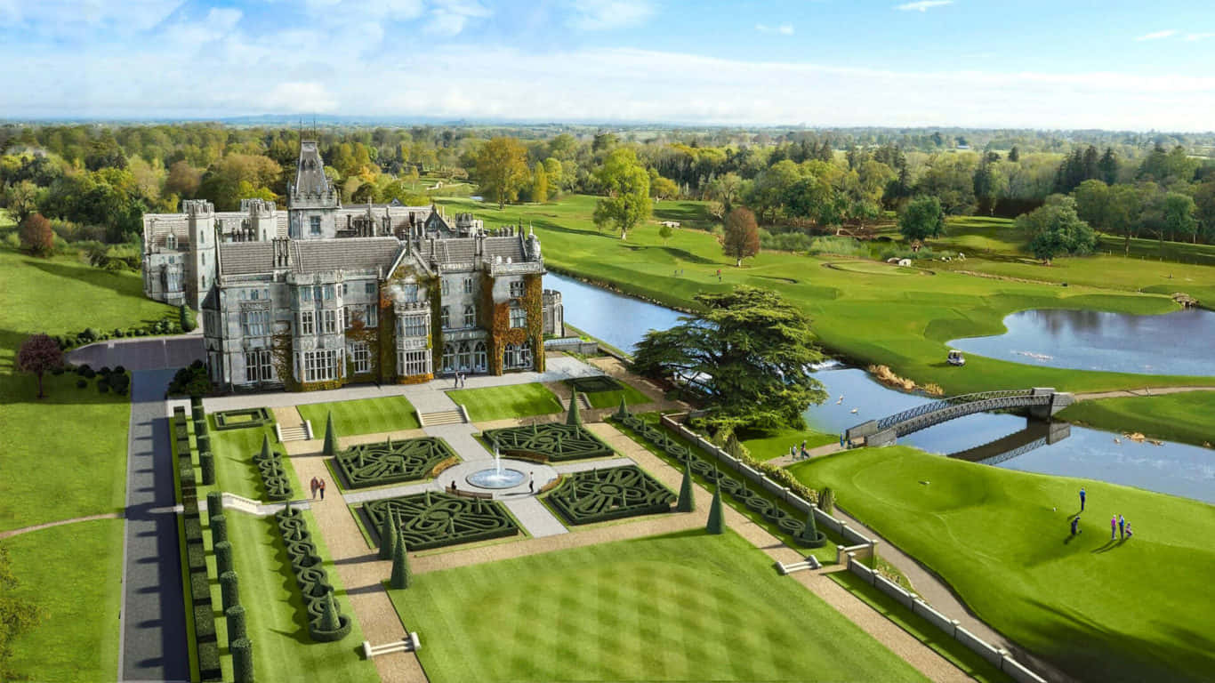 1366x768 Golf Course 桌布 壁紙 — 一座宏偉的石頭城堡，擁有修剪整齊的花園，以及一條蜿蜒的河流流經鬱鬱蔥蔥的高爾夫球場，上方是明亮的藍天。