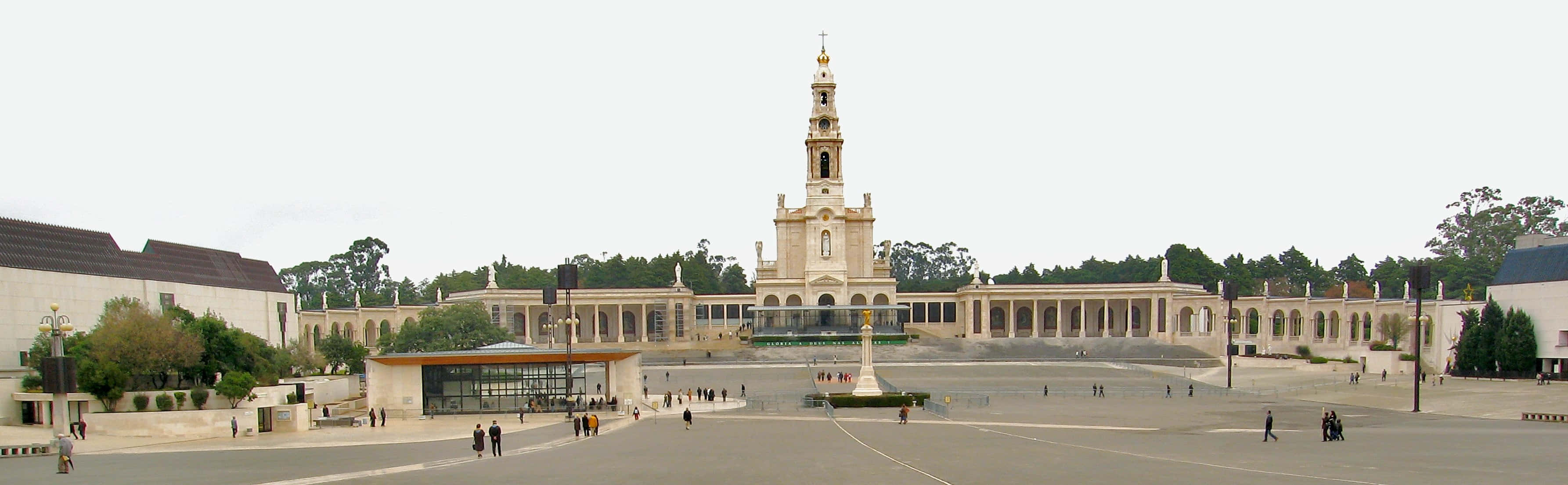 Portugal 桌布 壁紙 — 一座宏偉的米色大教堂，帶有高高的鐘樓，矗立在廣闊廣場的中央，周圍環繞著樹木和遊客。