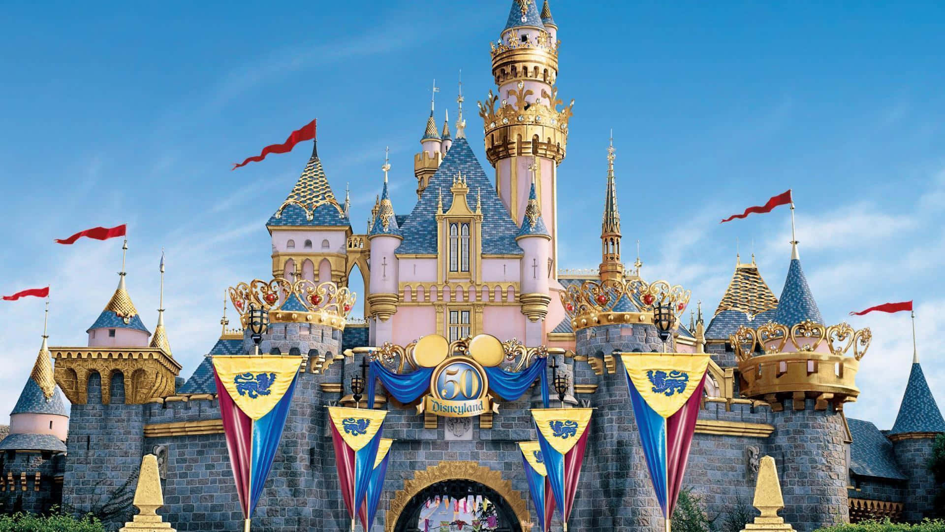Disneyland 桌布 壁紙 — 一座宏偉的粉紅色和金色城堡，擁有藍色瓦片屋頂和紅色旗幟，矗立在清澈的藍天下。