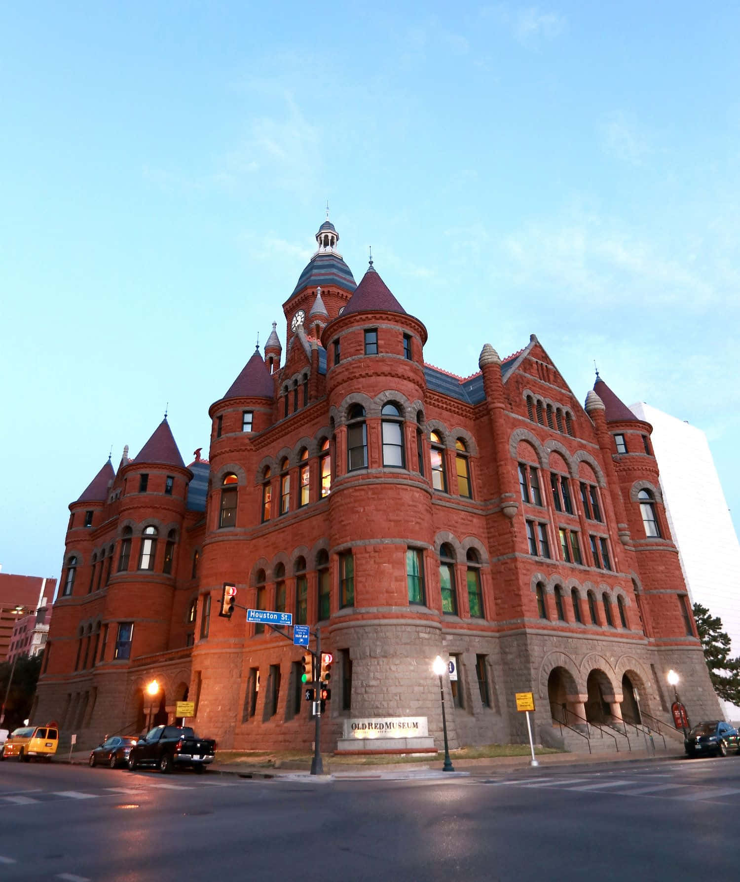 Court 桌布 壁紙 — 一座宏偉的紅磚歷史博物館建築，帶有塔樓和拱形窗戶，在黃昏時分對著清澈的藍天溫暖地發光。