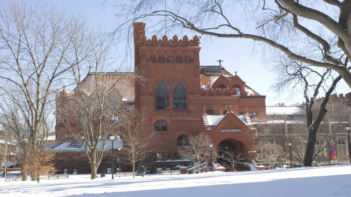 University Of Pennsylvania 桌布 壁紙 — 一座宏偉的紅磚歷史建築在清澈的藍天下巍然聳立，周圍是白雪覆蓋的地面和光禿的冬季樹木。