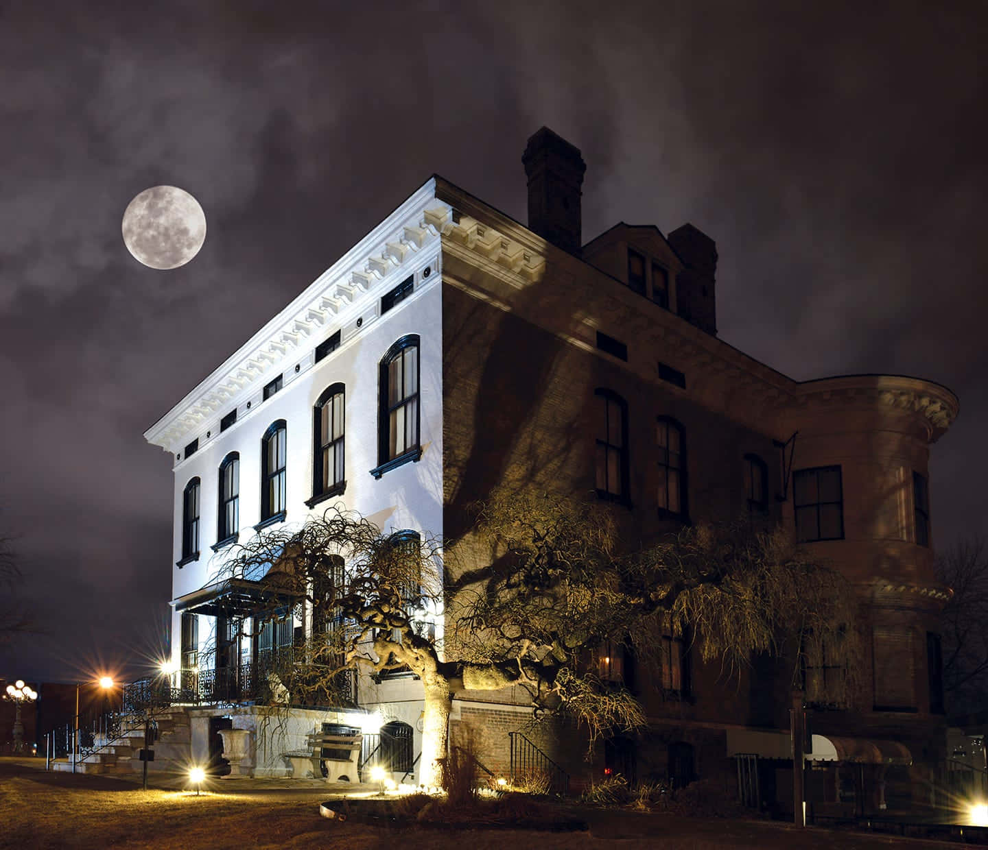 Haunted House 桌布 壁紙 — 一座宏偉的維多利亞式房屋在滿月下的夜晚被照亮，光禿禿的樹木投下陰影。