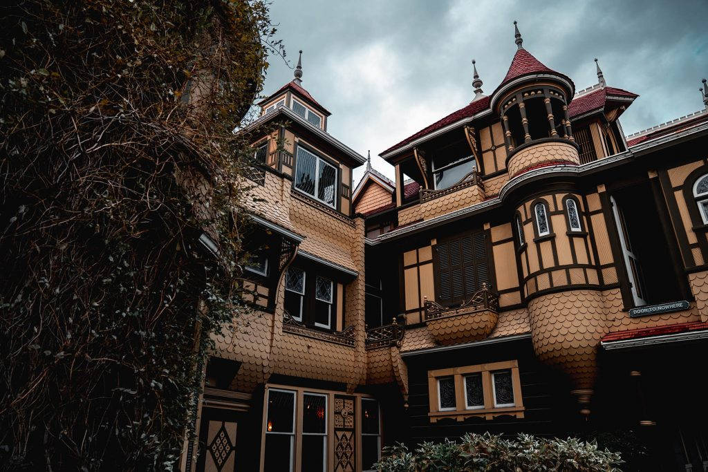 Mansion 桌布 壁紙 — 一座宏偉的維多利亞式豪宅，擁有華麗的塔樓和常春藤覆蓋的牆壁，在陰沉的灰色天空下。