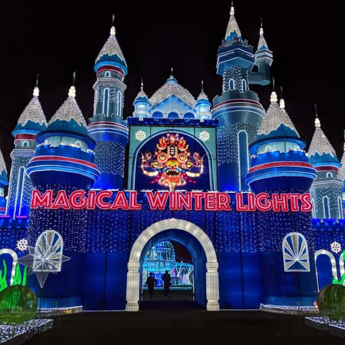 magical 桌布 壁紙 — 一座宏偉的藍色城堡在黑暗的夜空下亮起，帶有紅色霓虹燈牌，上面寫著魔幻冬季燈光。