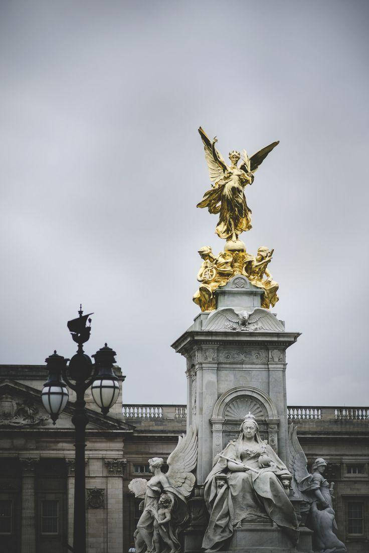 England 桌布 壁紙 — 一座宏偉的金色天使雕像矗立在石製紀念碑頂端，背景是陰雲密布的天空，下方是古典建築。