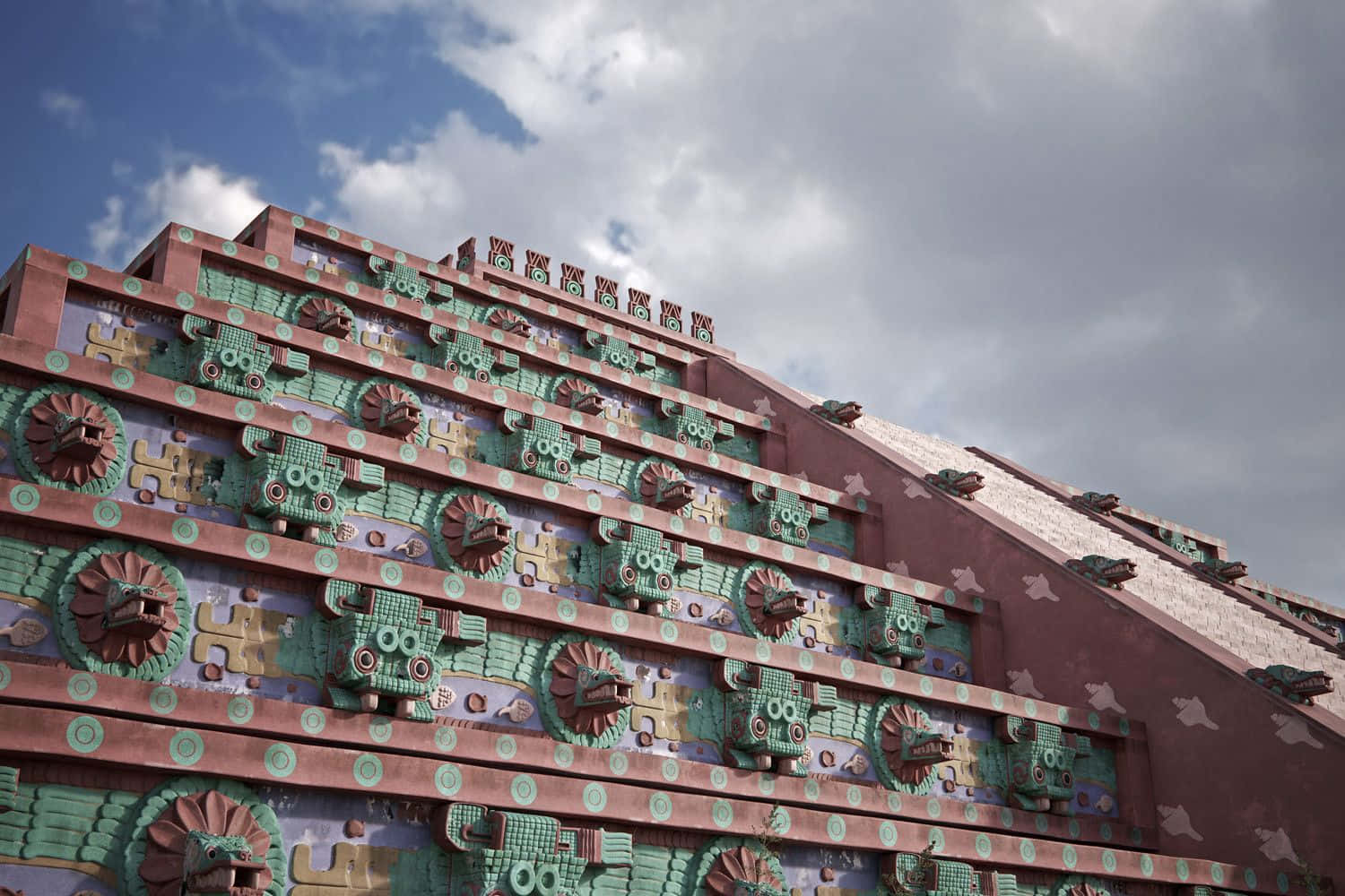 The Citadel 桌布 壁紙 — 一座宏偉的階梯金字塔，在陰天天空下飾有複雜的綠色和紅色馬賽克蛇頭。