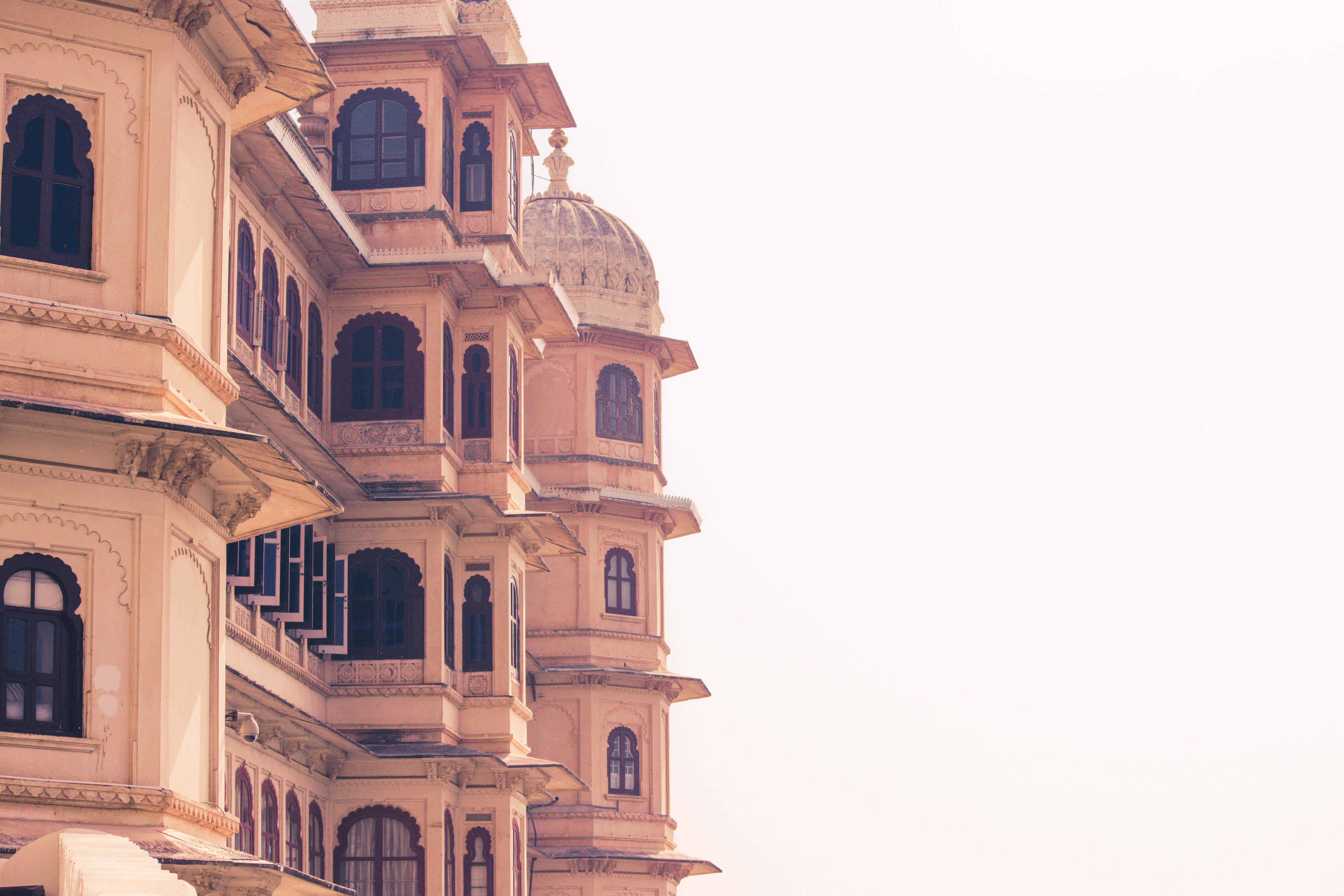 Rajasthan 桌布 壁紙 — 一座宏大的米色宮殿，擁有精緻的陽台和圓頂，矗立在柔和朦朧的天空下。
