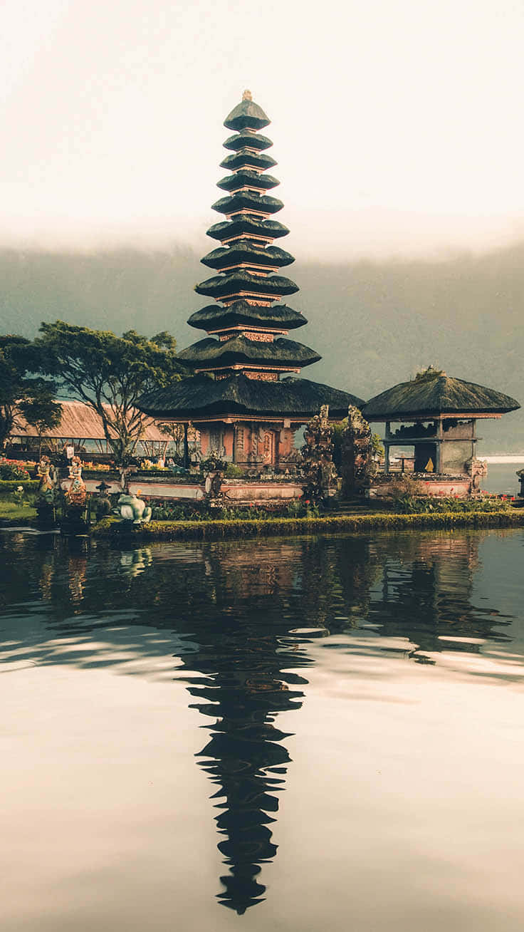 Asian 桌布 壁紙 — 一座寧靜的峇里島寺廟，層疊的屋頂在平靜的水面上完美倒映，天空柔和迷濛。