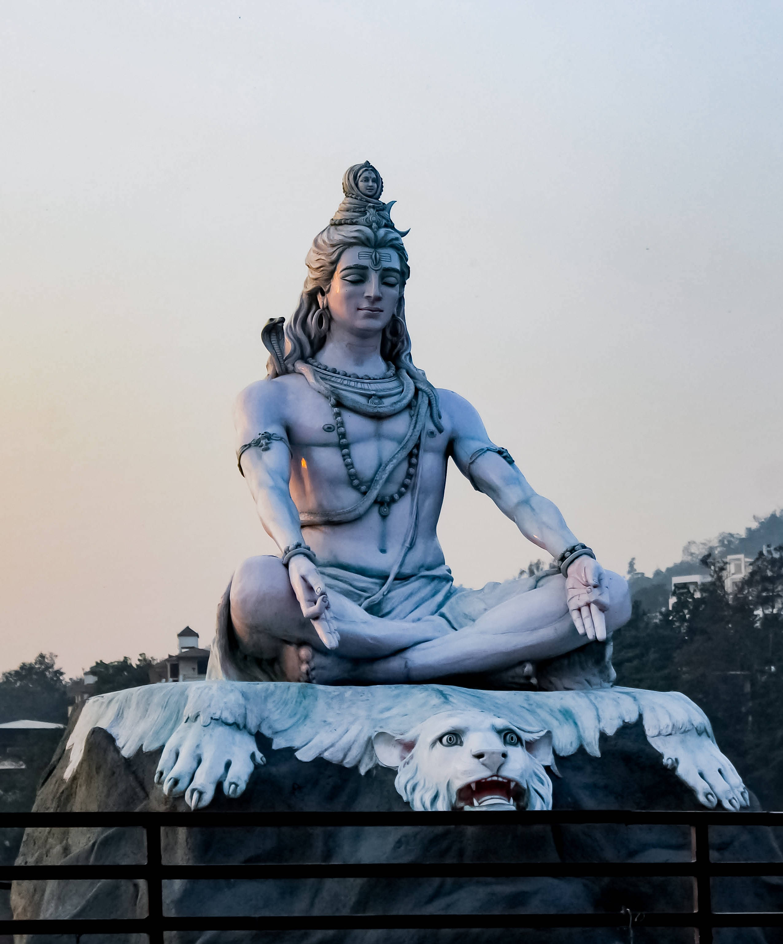 bholenath 桌布 壁紙 — 一座寧靜的白色石雕濕婆神像，在黃昏時分柔和環境光中，於咆哮的獅子上冥想。