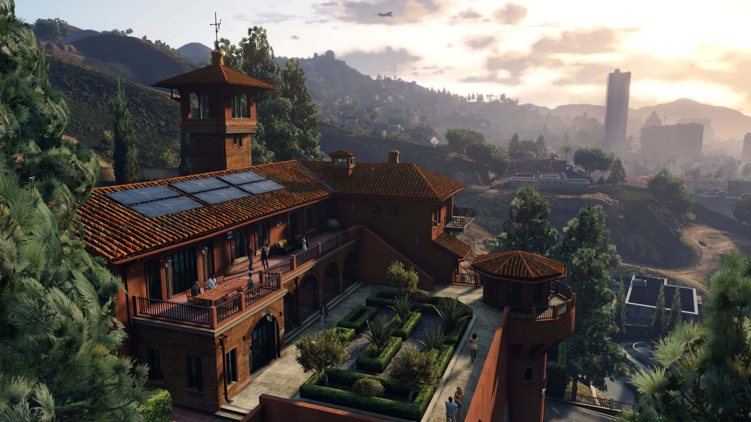 Grand Theft Auto V 桌布 壁紙 — 一座寬敞的地中海風格別墅，擁有陶土屋頂和太陽能板，坐落在山頂上，俯瞰著金色時刻朦朧的城市景觀。