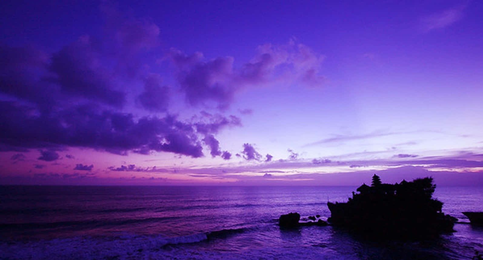 Blue And Purple Sunset 桌布 壁紙 — 一座寺廟的剪影矗立在岩石島上，在黃昏時分，天空呈現鮮豔的紫色和粉紅色。