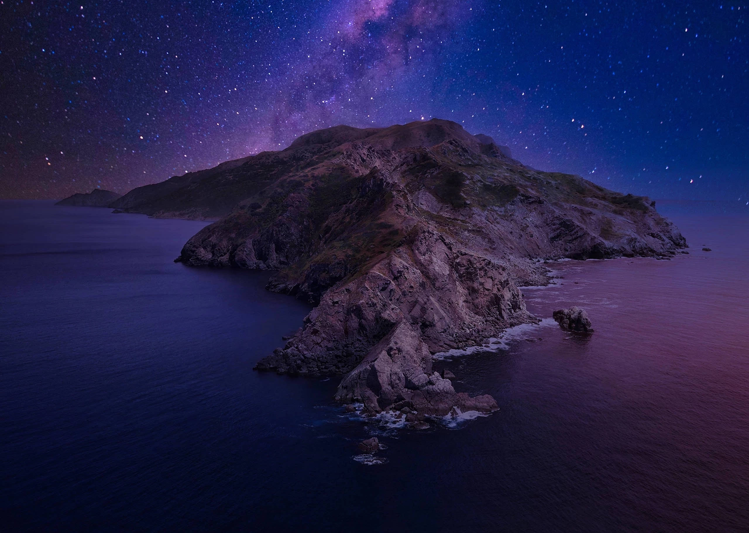 Catalina 桌布 壁紙 — 一座崎嶇的島嶼從深紫色的海水中升起，星空下有一條發光的紫色銀河。