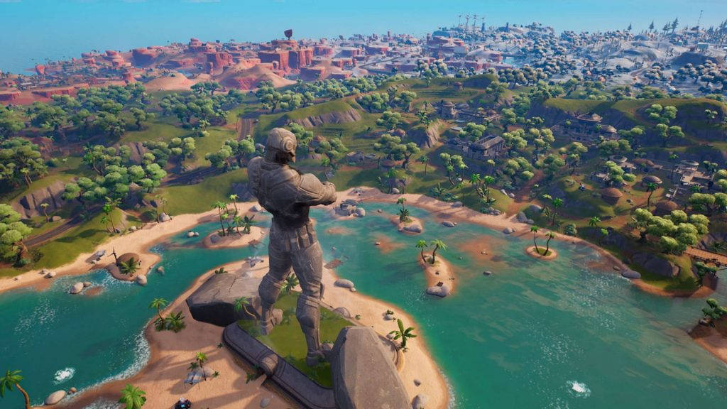 Fortnite Chapter 3 桌布 壁紙 — 一座巨型雕像俯瞰著一個充滿活力的熱帶島嶼，島上有碧綠的海水和遠處的紅岩城市，天空清澈湛藍。
